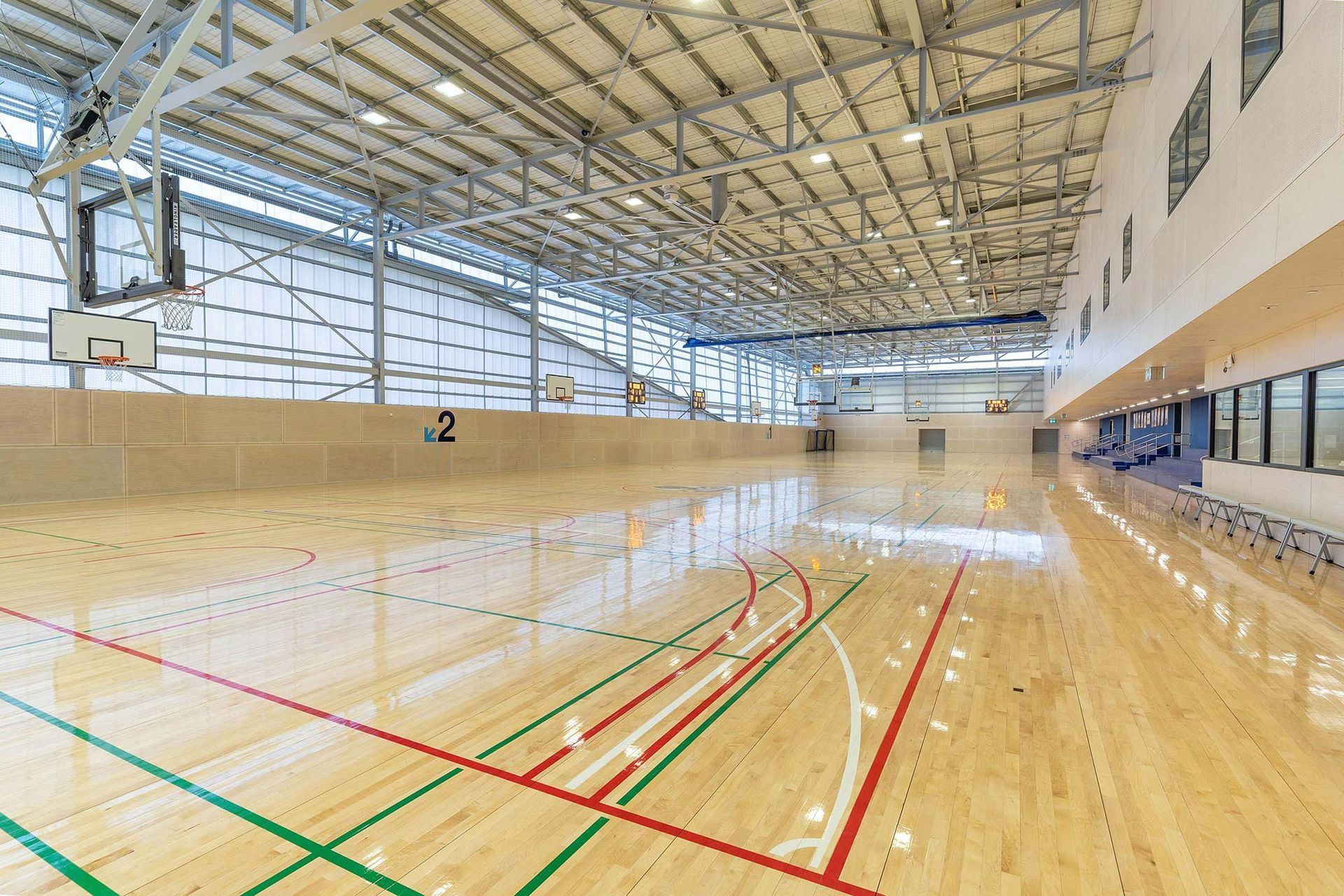 A large indoor basketball court with a wooden floor and a basketball hoop.
