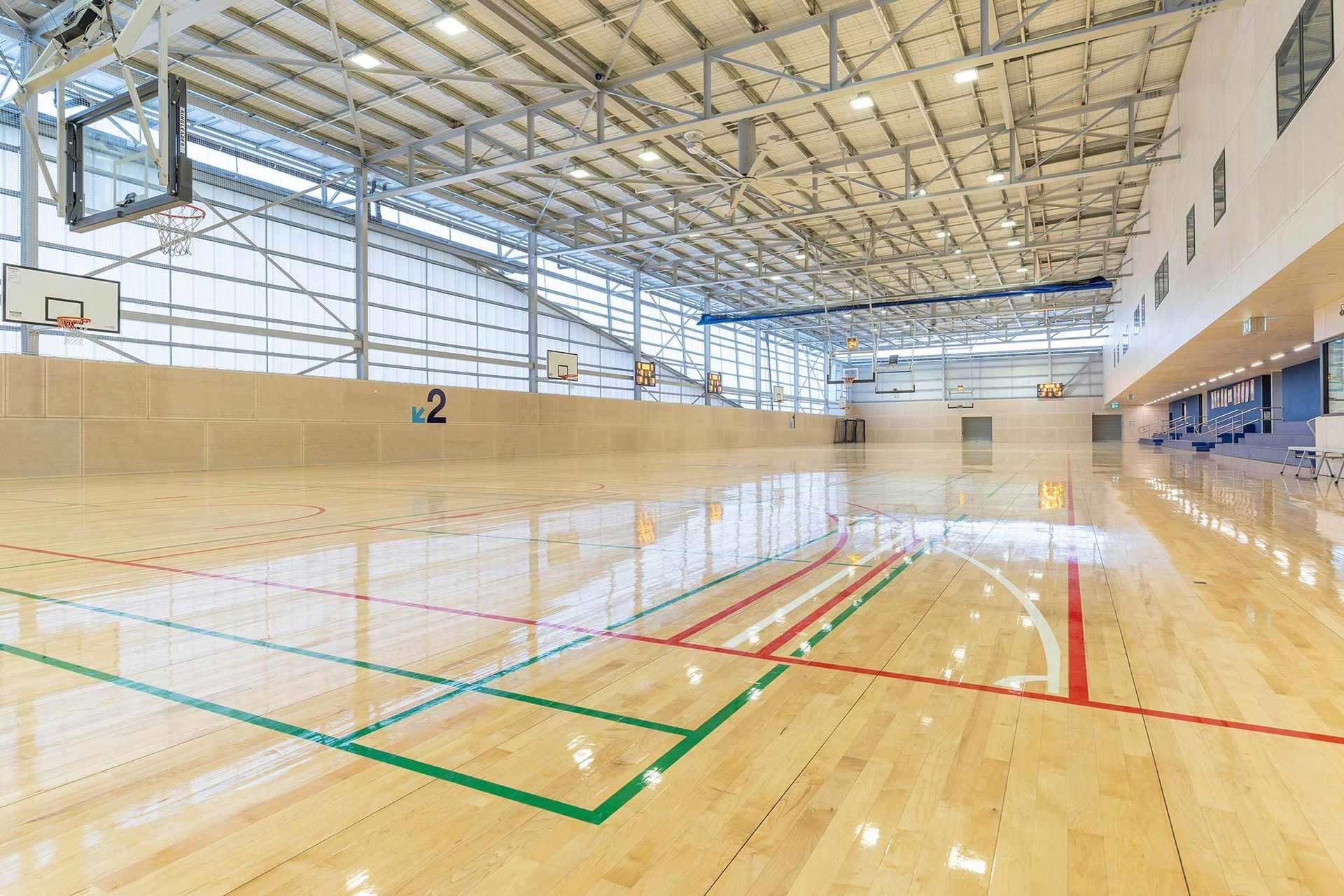 A large indoor basketball court with a wooden floor and a basketball hoop.