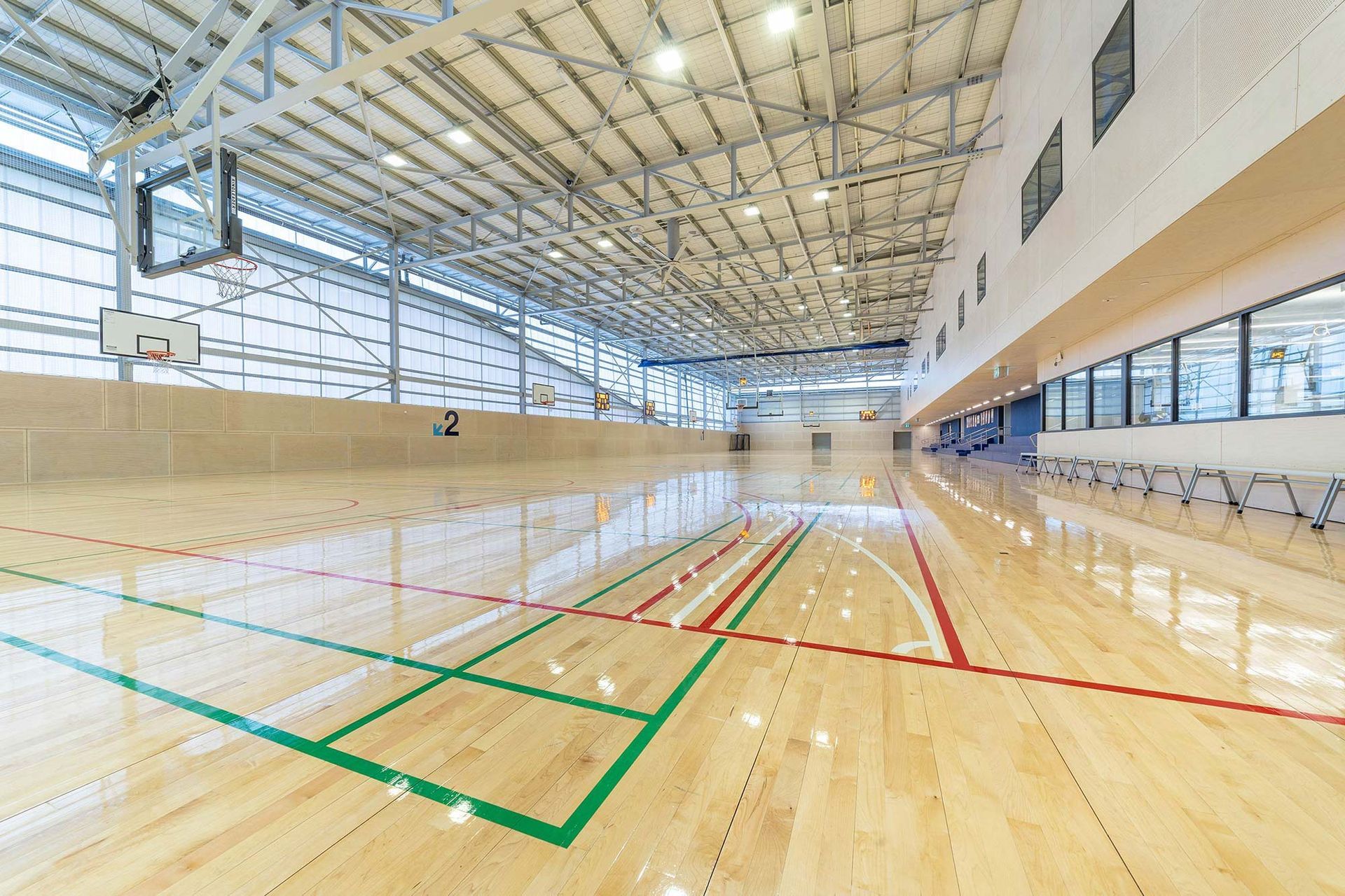 A large indoor basketball court with a wooden floor and a basketball hoop.