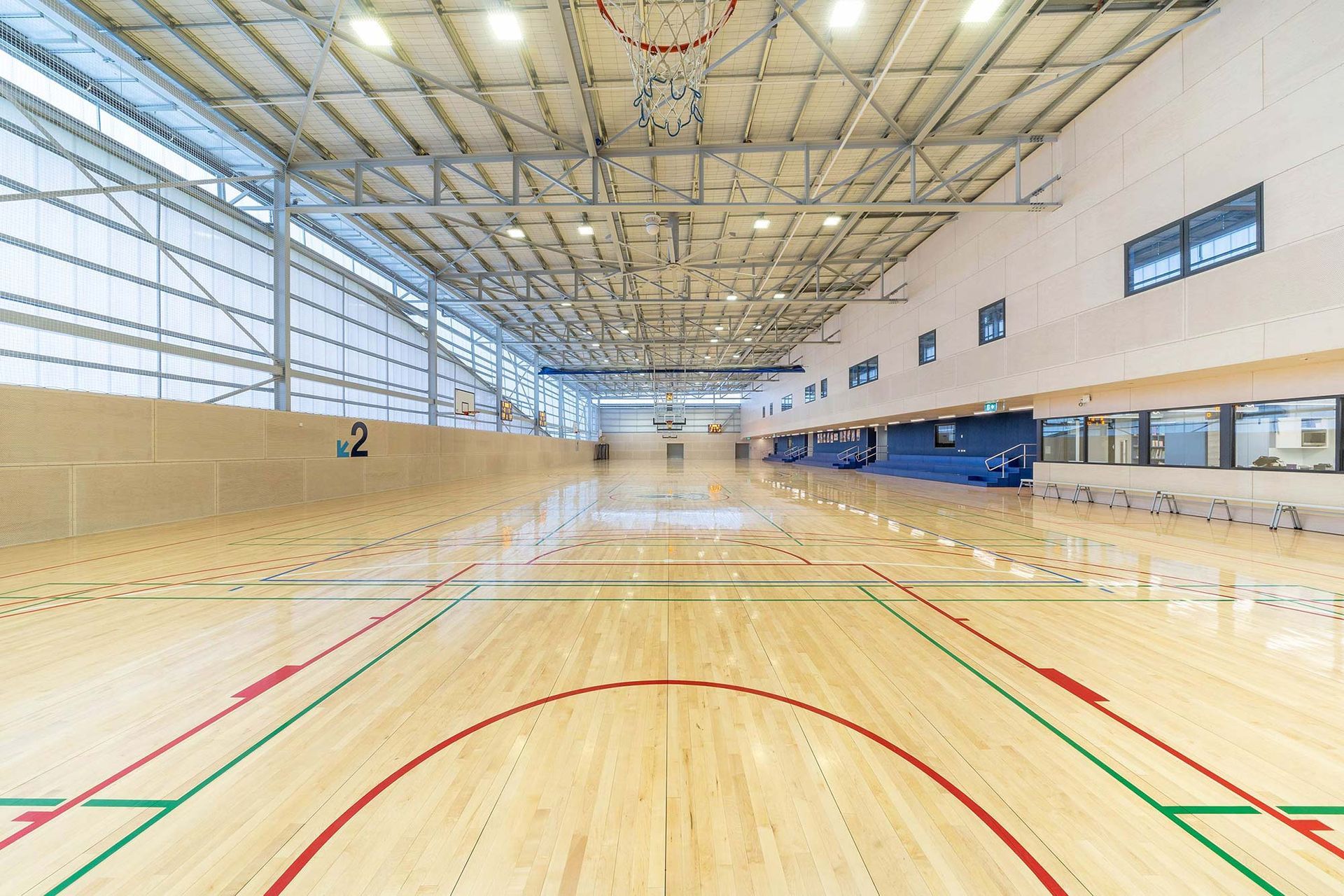 A large indoor basketball court with a wooden floor and a basketball hoop.