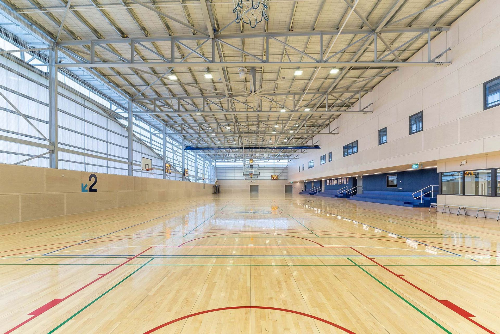 A large indoor basketball court with a wooden floor and a basketball hoop.