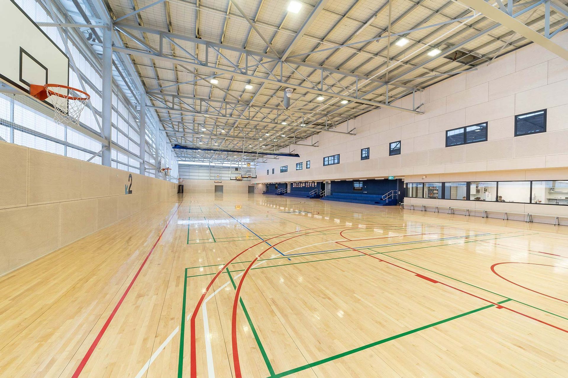 A large indoor basketball court with a wooden floor and a basketball hoop.
