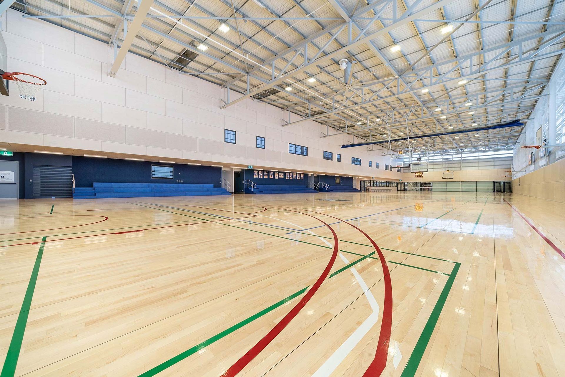 A large indoor basketball court with a wooden floor and a basketball hoop.