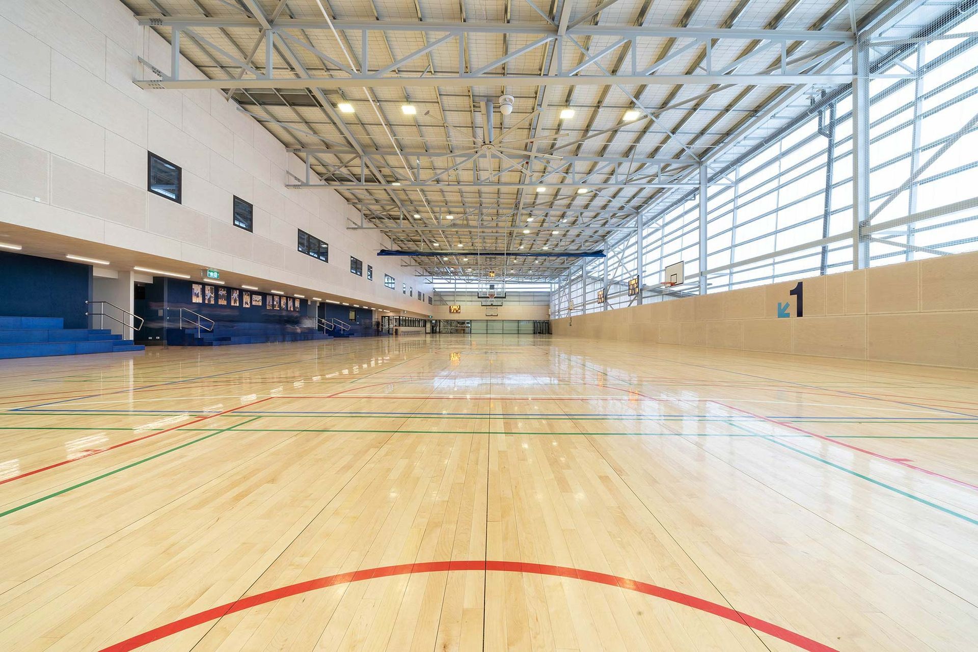 A large indoor basketball court with a wooden floor and a red circle in the middle.