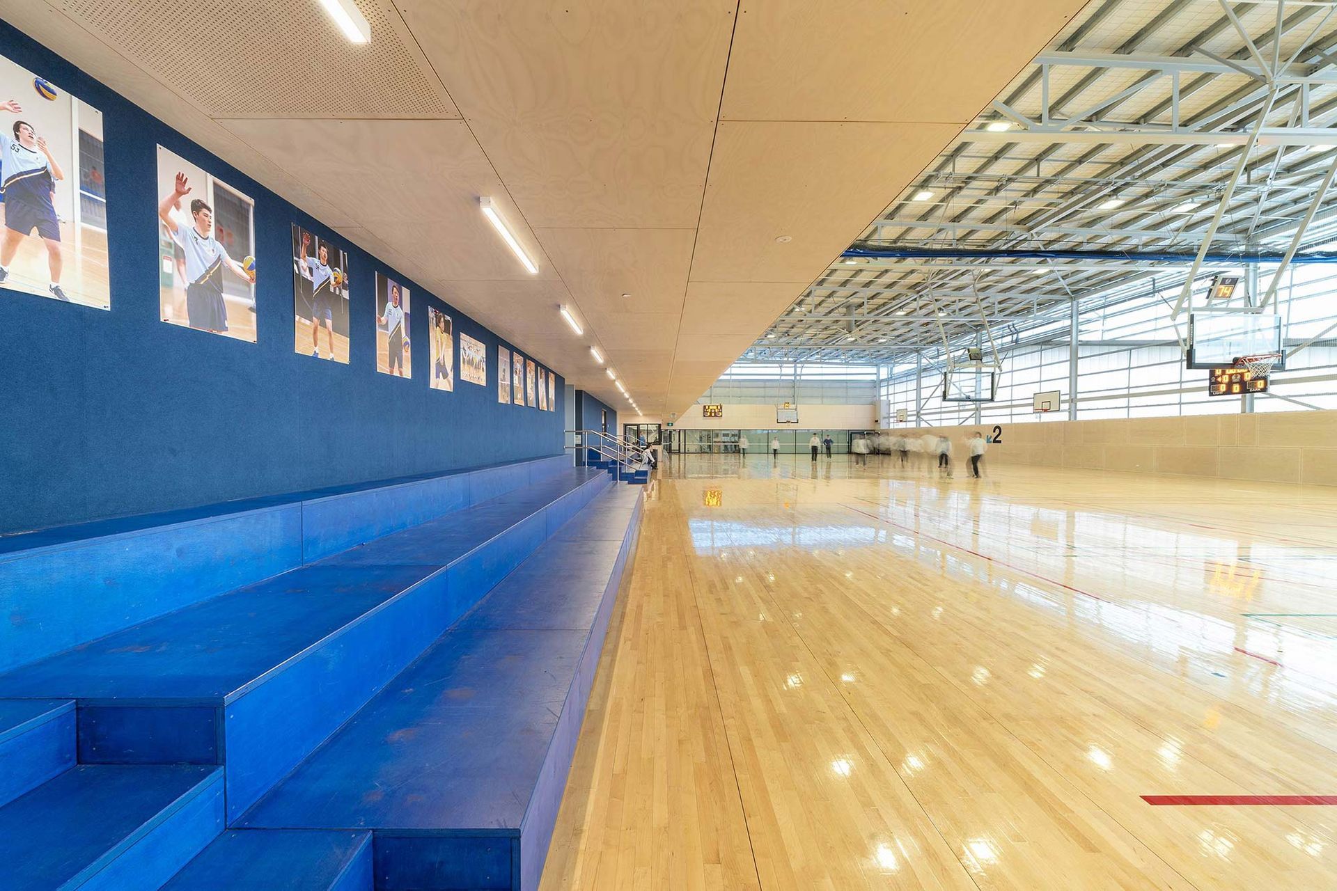 A large indoor basketball court with bleachers and pictures on the wall.
