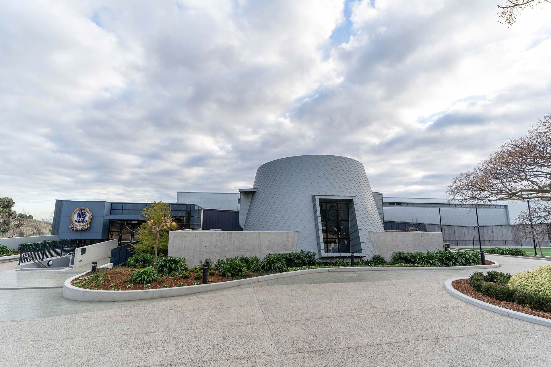 A large building with a dome shaped roof is surrounded by gravel and trees.