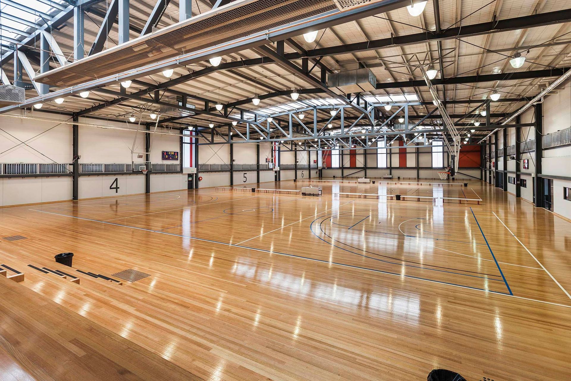 A large empty gym with a wooden floor and a basketball court.