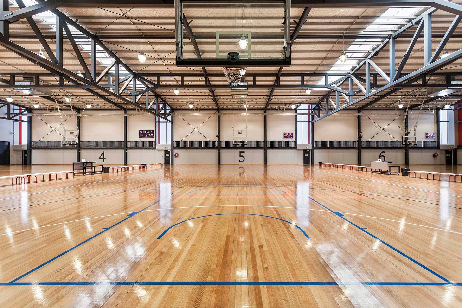 An empty basketball court with a wooden floor and a basketball hoop