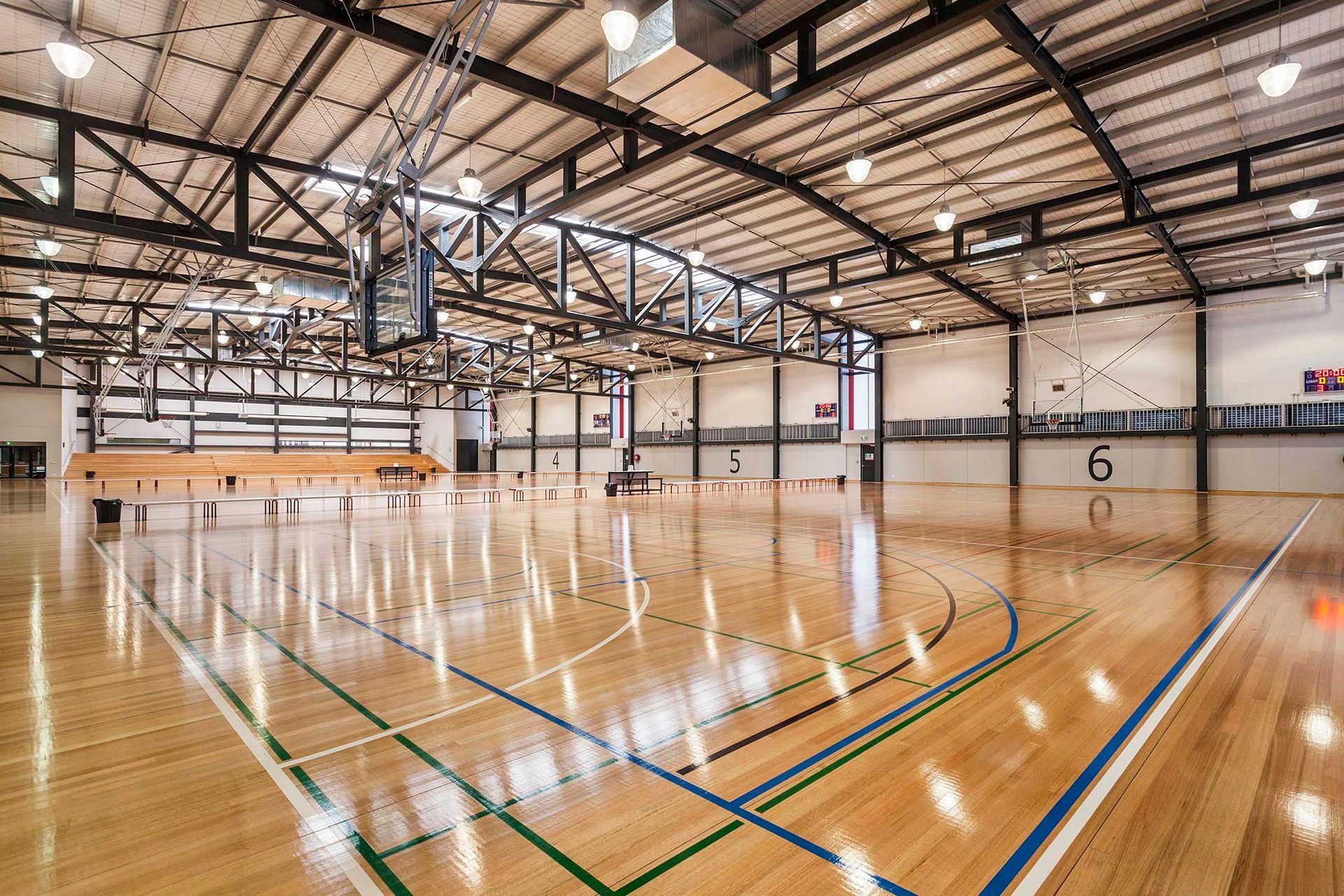 A large indoor basketball court with a wooden floor and a basketball hoop.