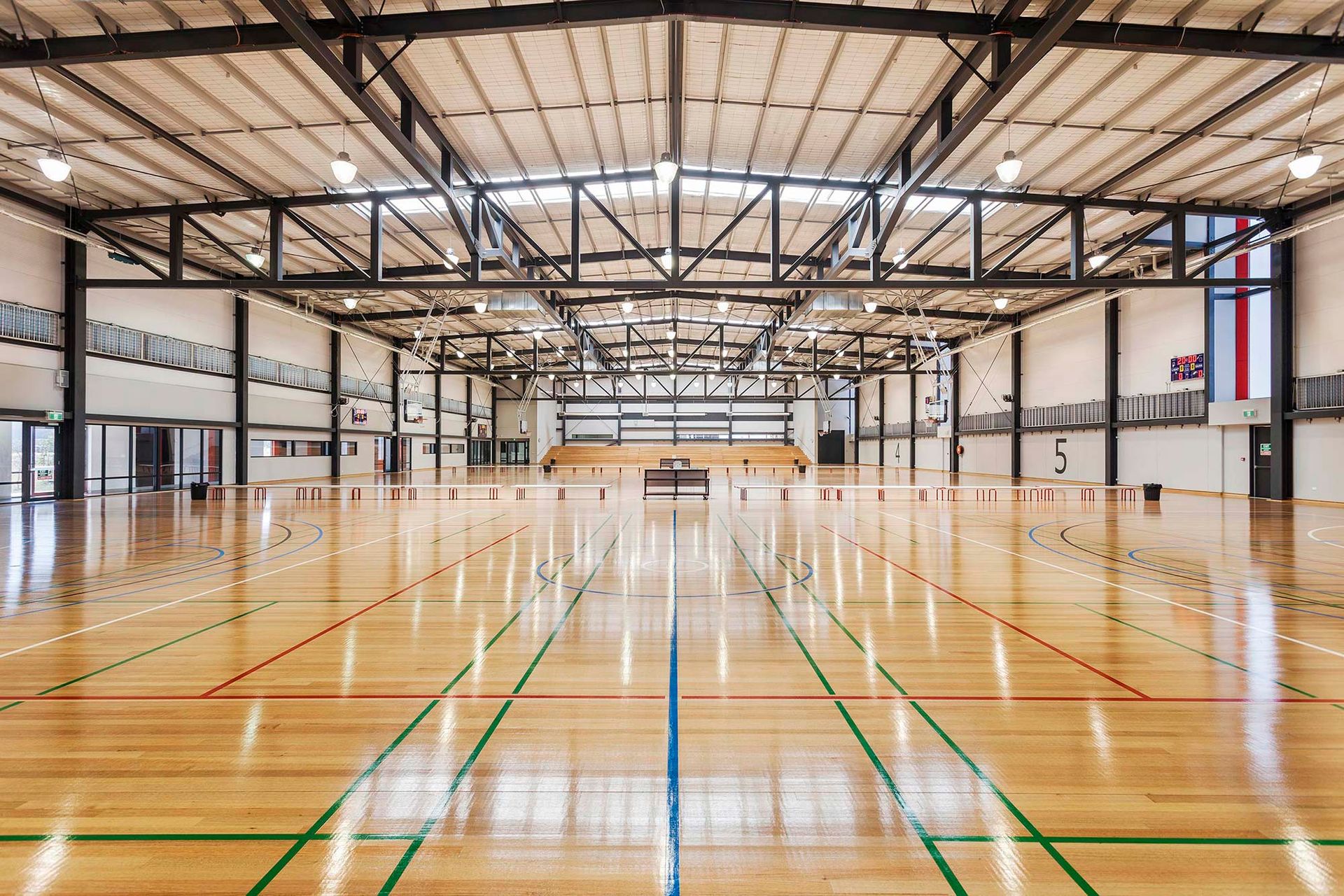 A large empty gym with a wooden floor and green lines.