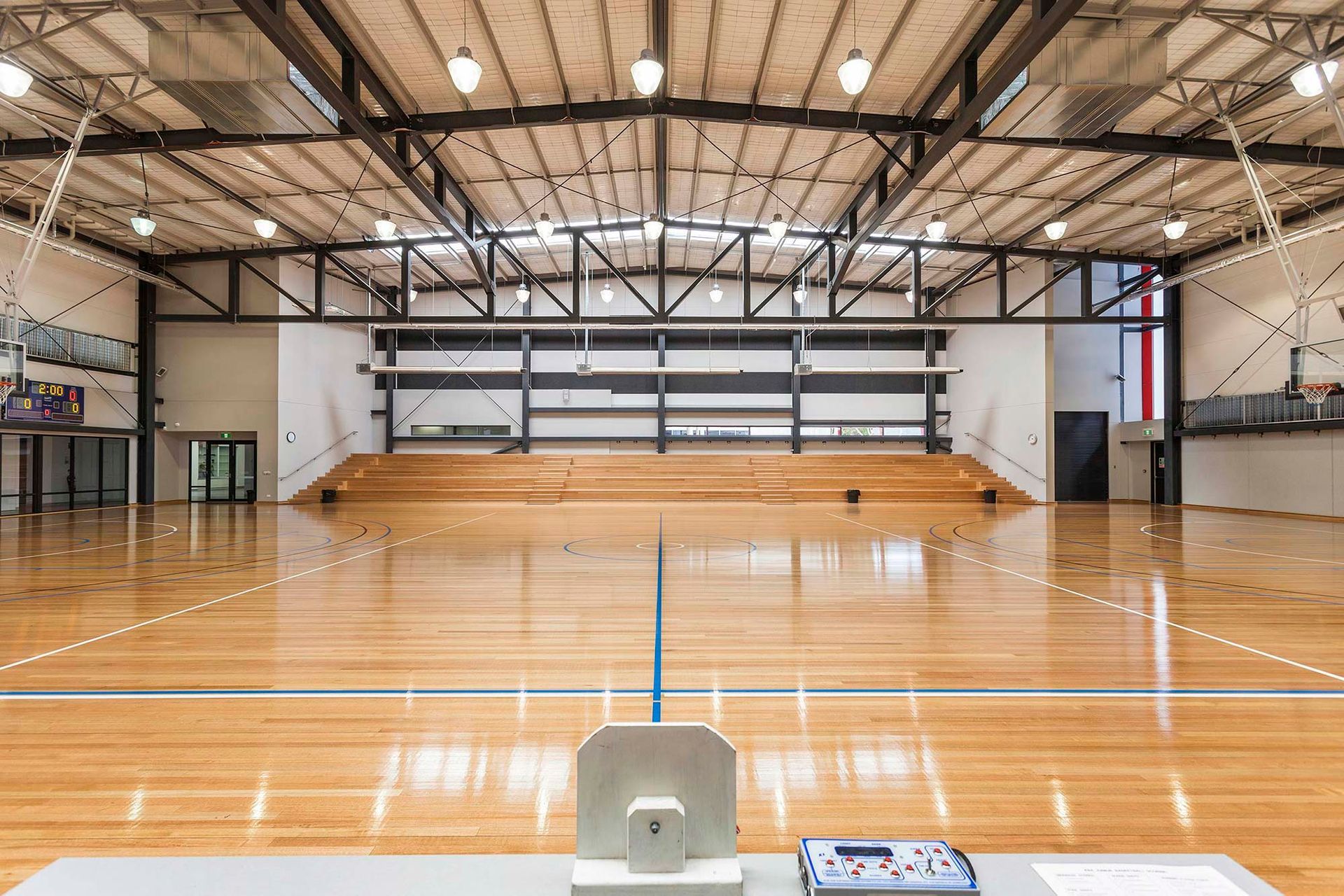 A large empty gym with a wooden floor and bleachers.