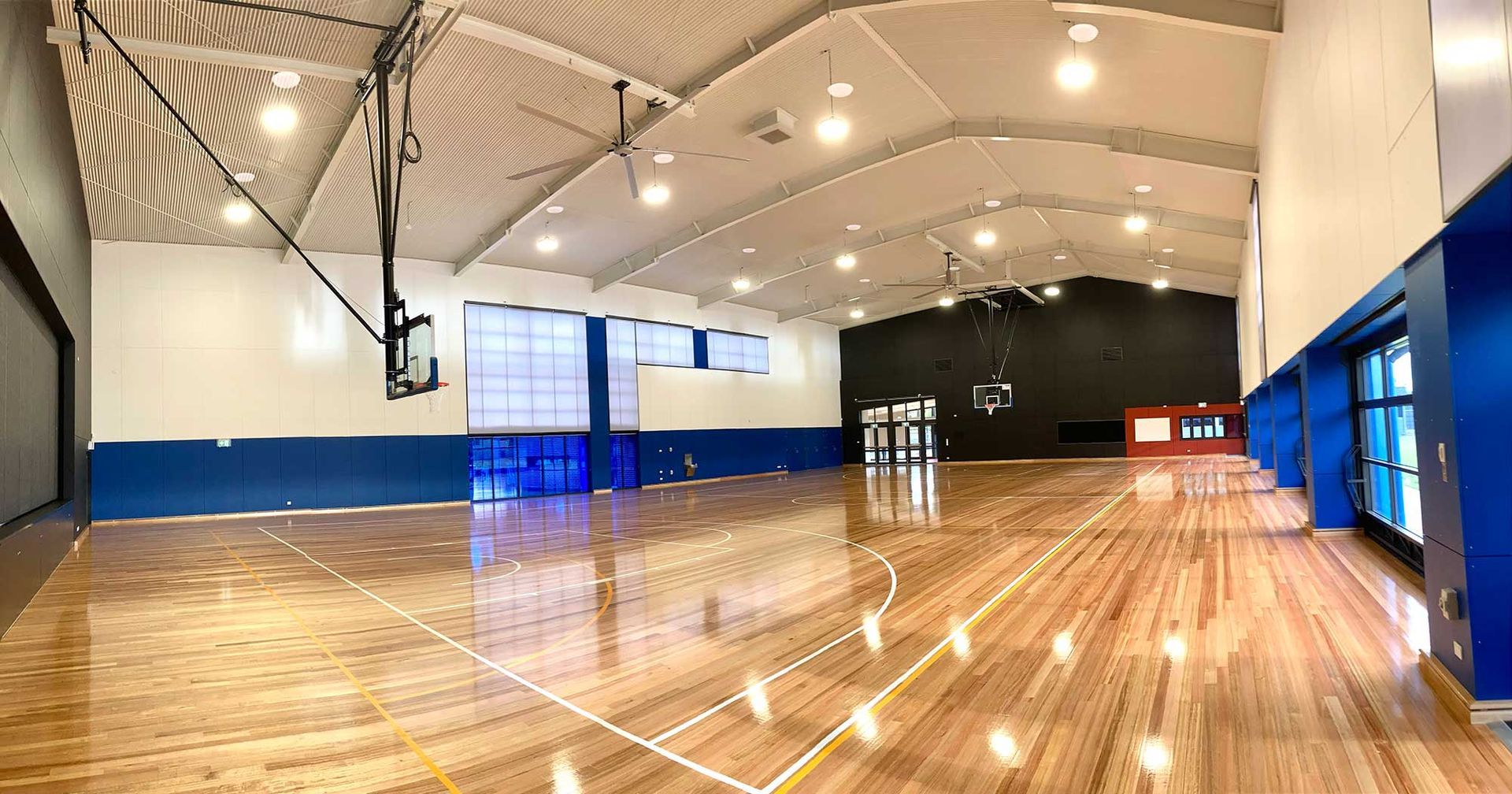 A large indoor basketball court with a wooden floor and a basketball hoop.
