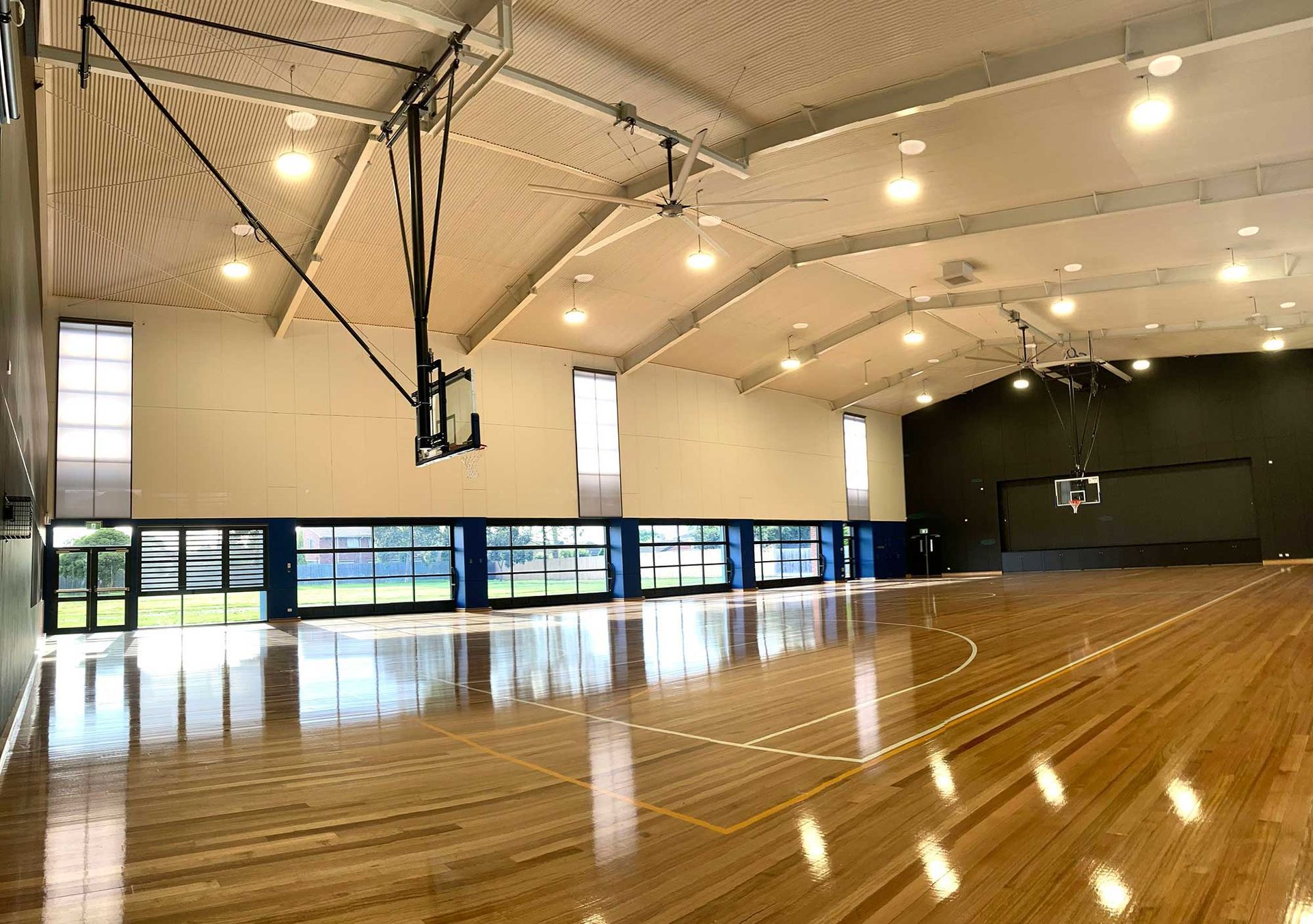 A large indoor basketball court with a wooden floor and a basketball hoop.
