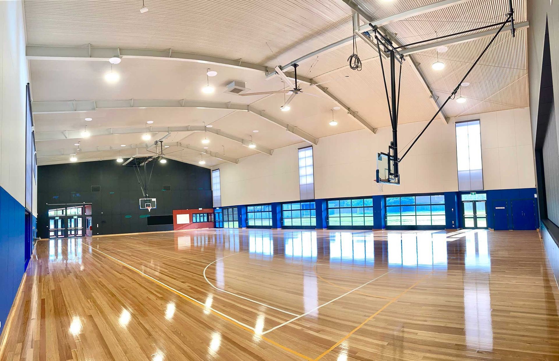 A large indoor basketball court with a wooden floor and a basketball hoop.