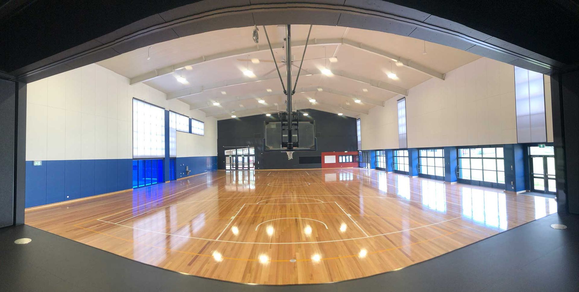 A large basketball court with a wooden floor and a basketball hoop.