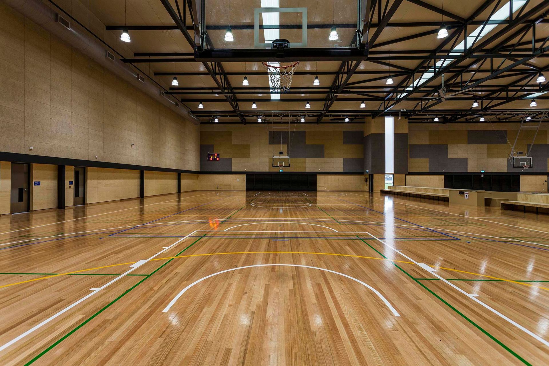 An empty basketball court with a wooden floor and a basketball hoop.