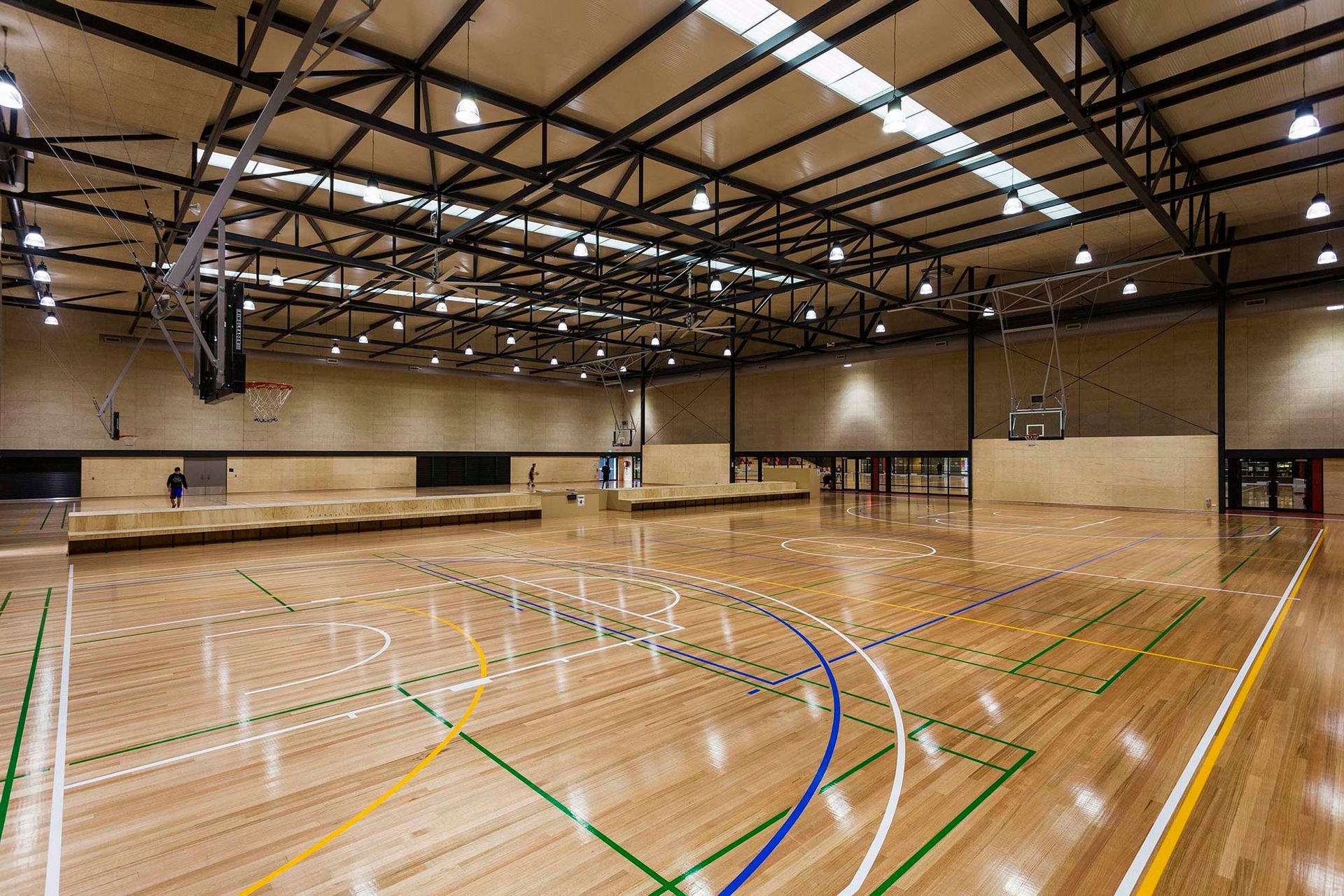 A large indoor basketball court with a wooden floor and a basketball hoop.