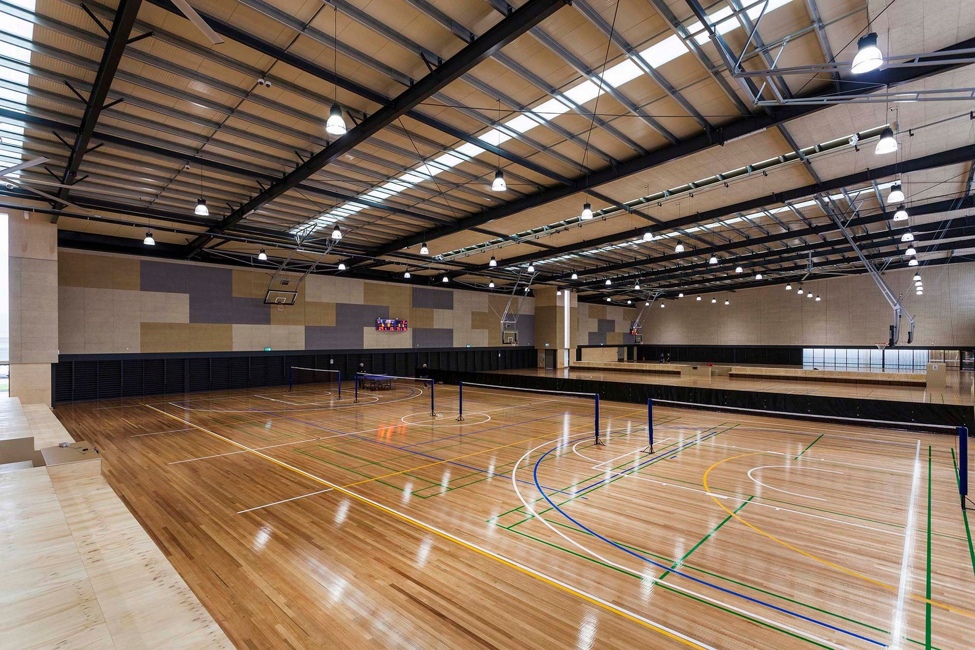A large indoor basketball court with a wooden floor and a basketball hoop.