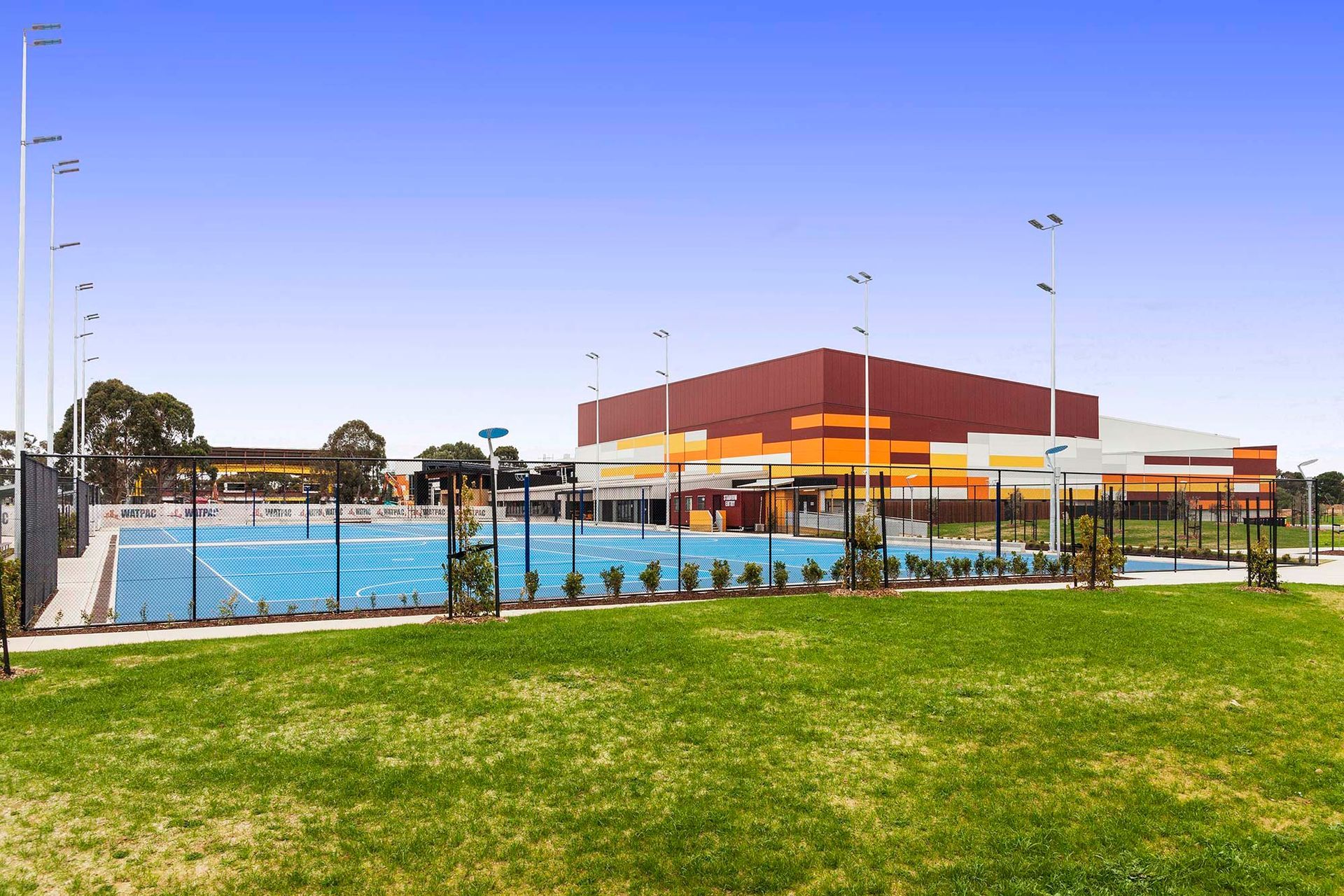 A large building with a pool and tennis courts in front of it.