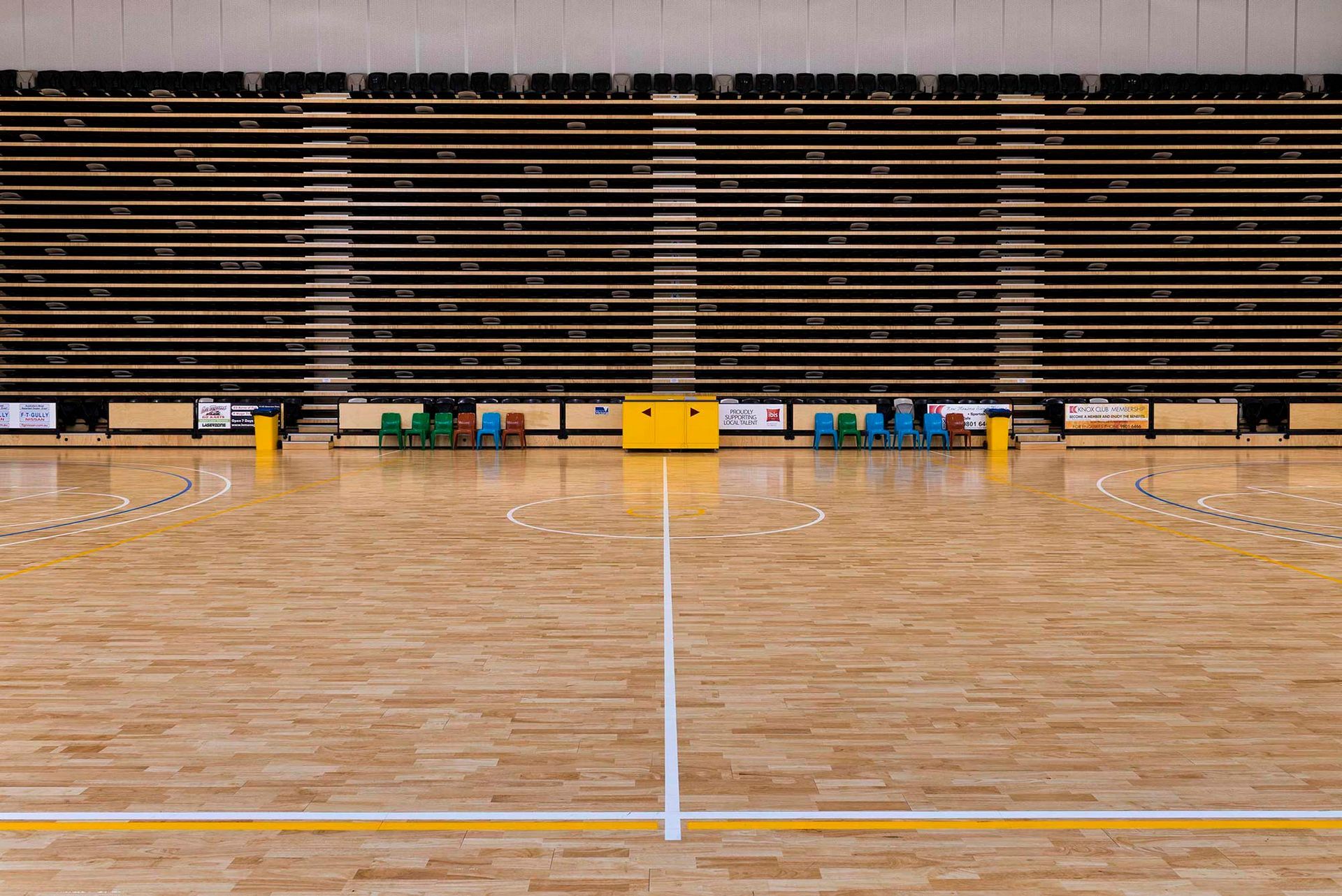 An empty basketball court with wooden floors and bleachers.