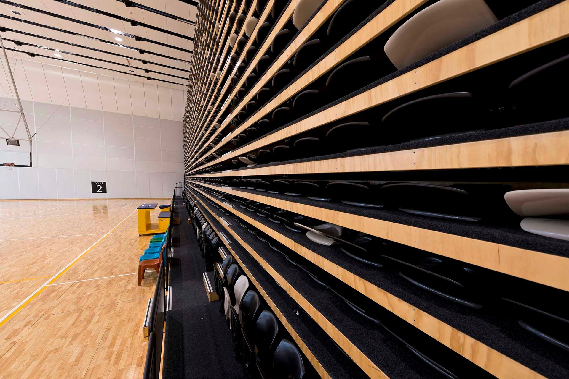A basketball court with a wooden wall and rows of chairs