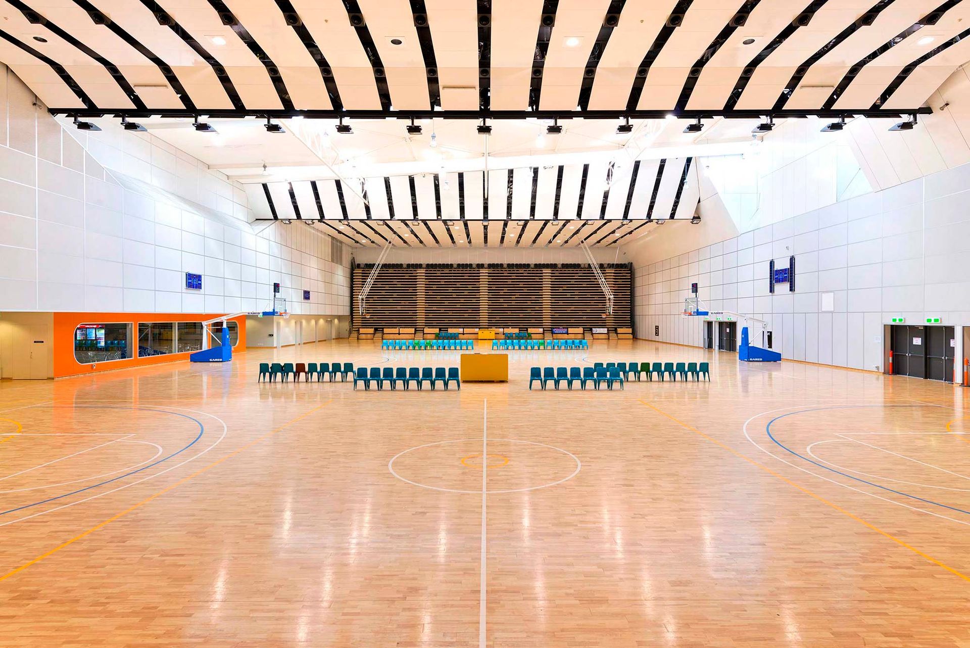 A large empty gym with a wooden floor and a basketball court.