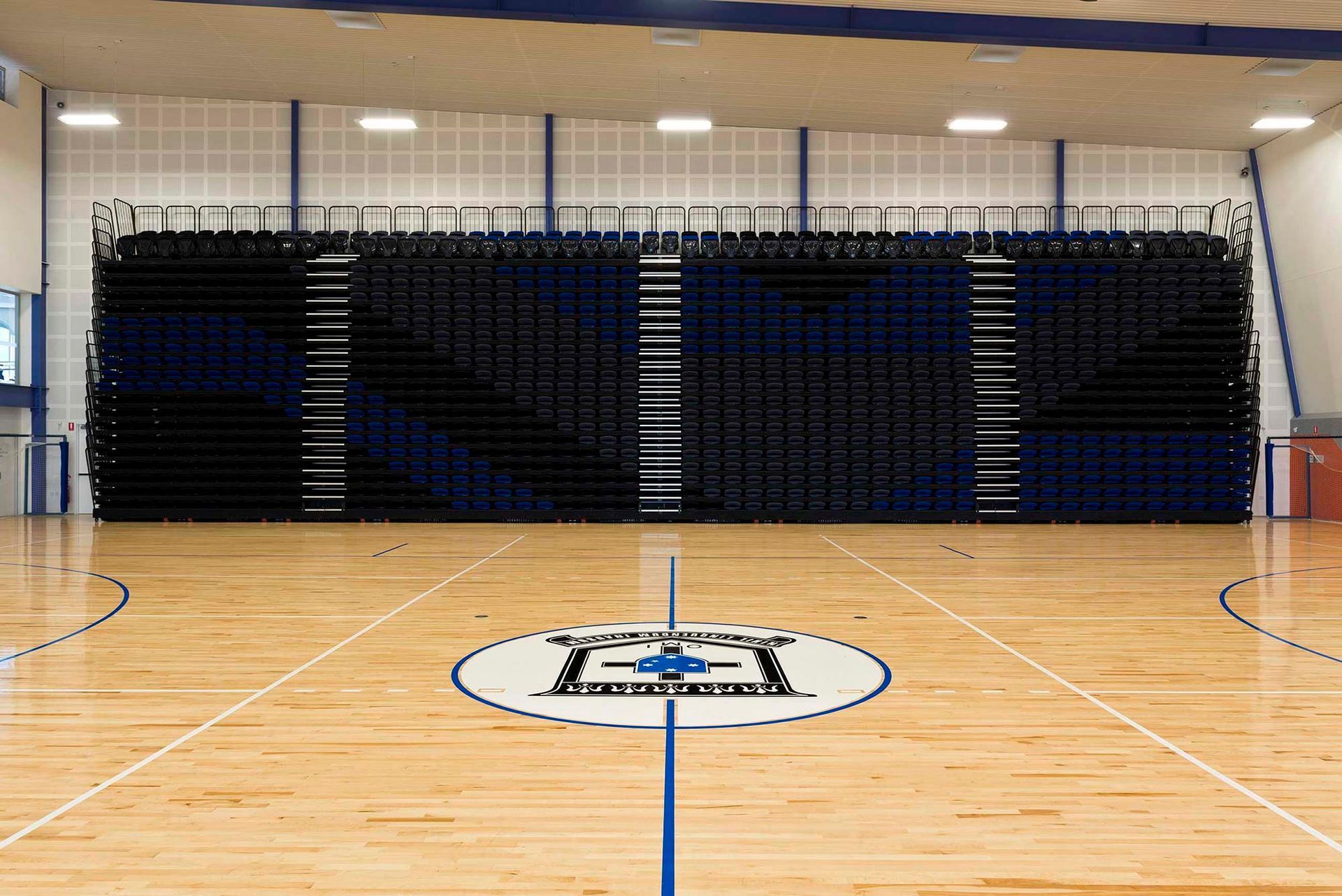 A wooden basketball court with a logo in the middle