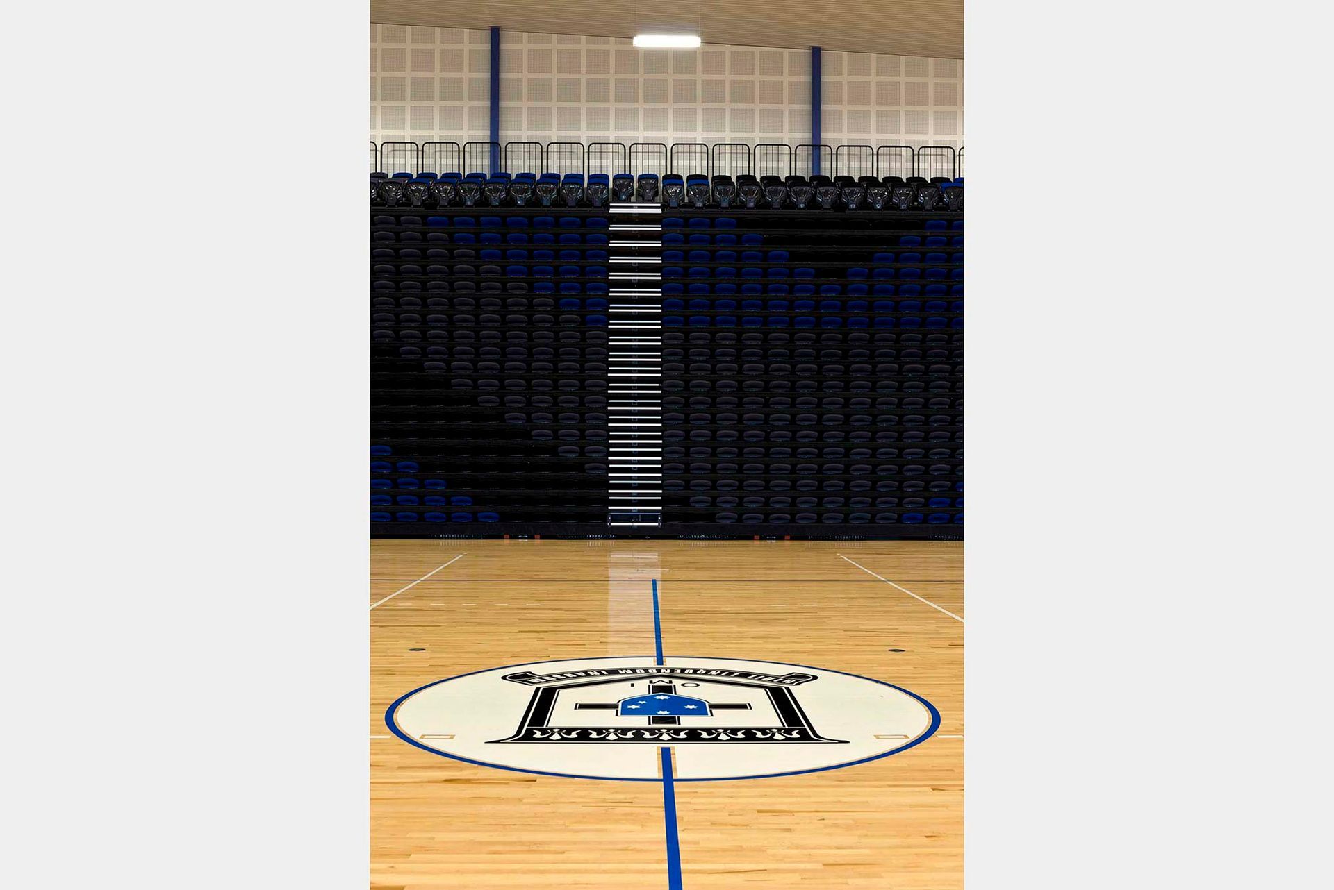 A basketball court with a logo on the floor and bleachers in the background.