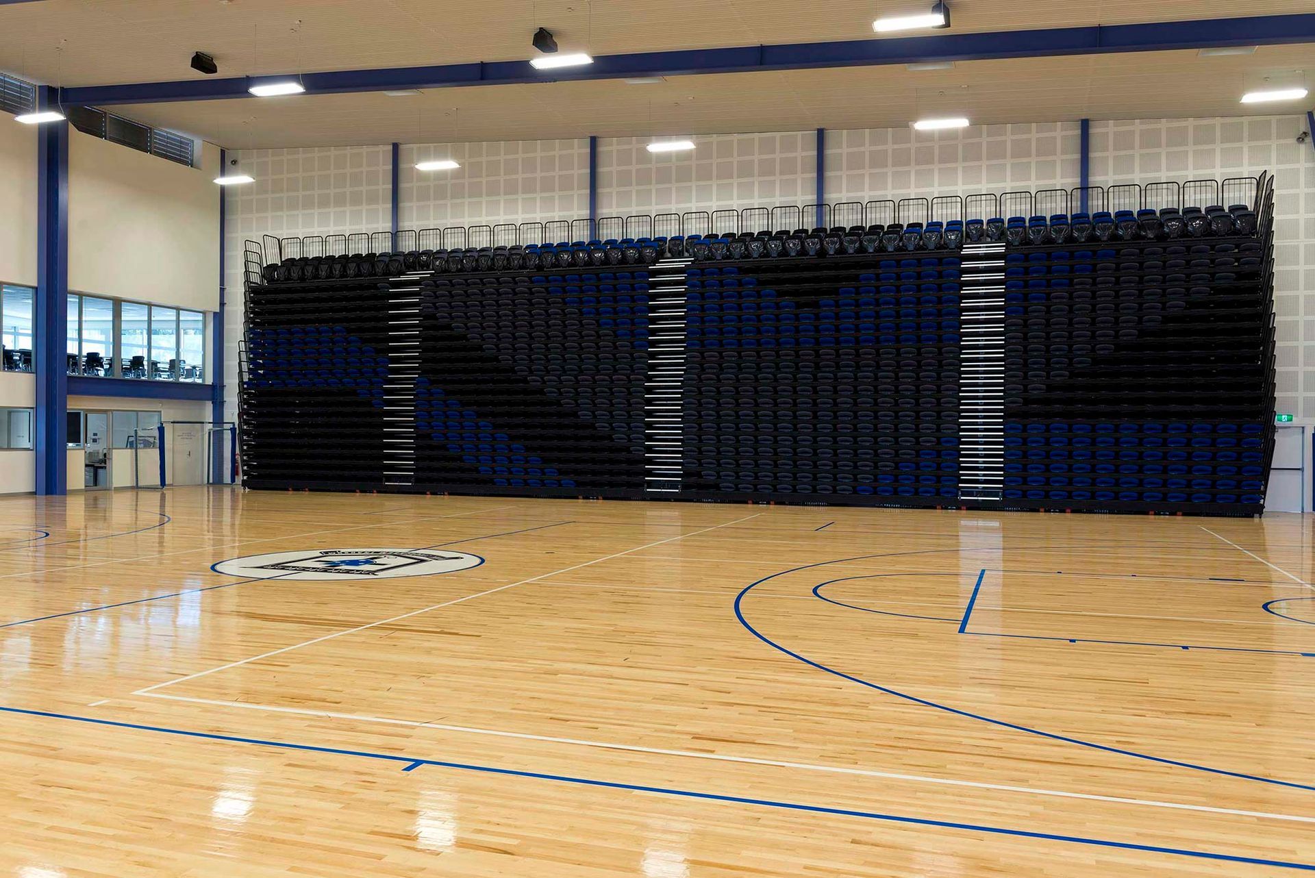 An empty basketball court with bleachers in the background