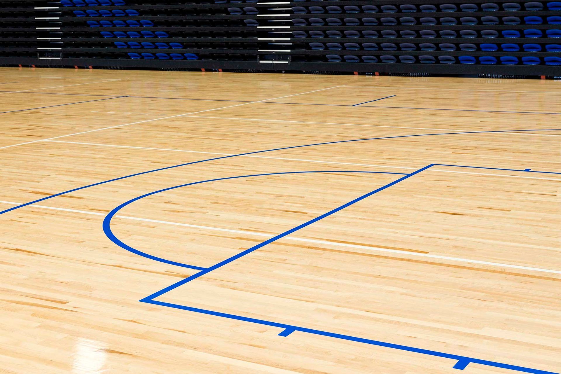 A wooden basketball court with blue lines on it