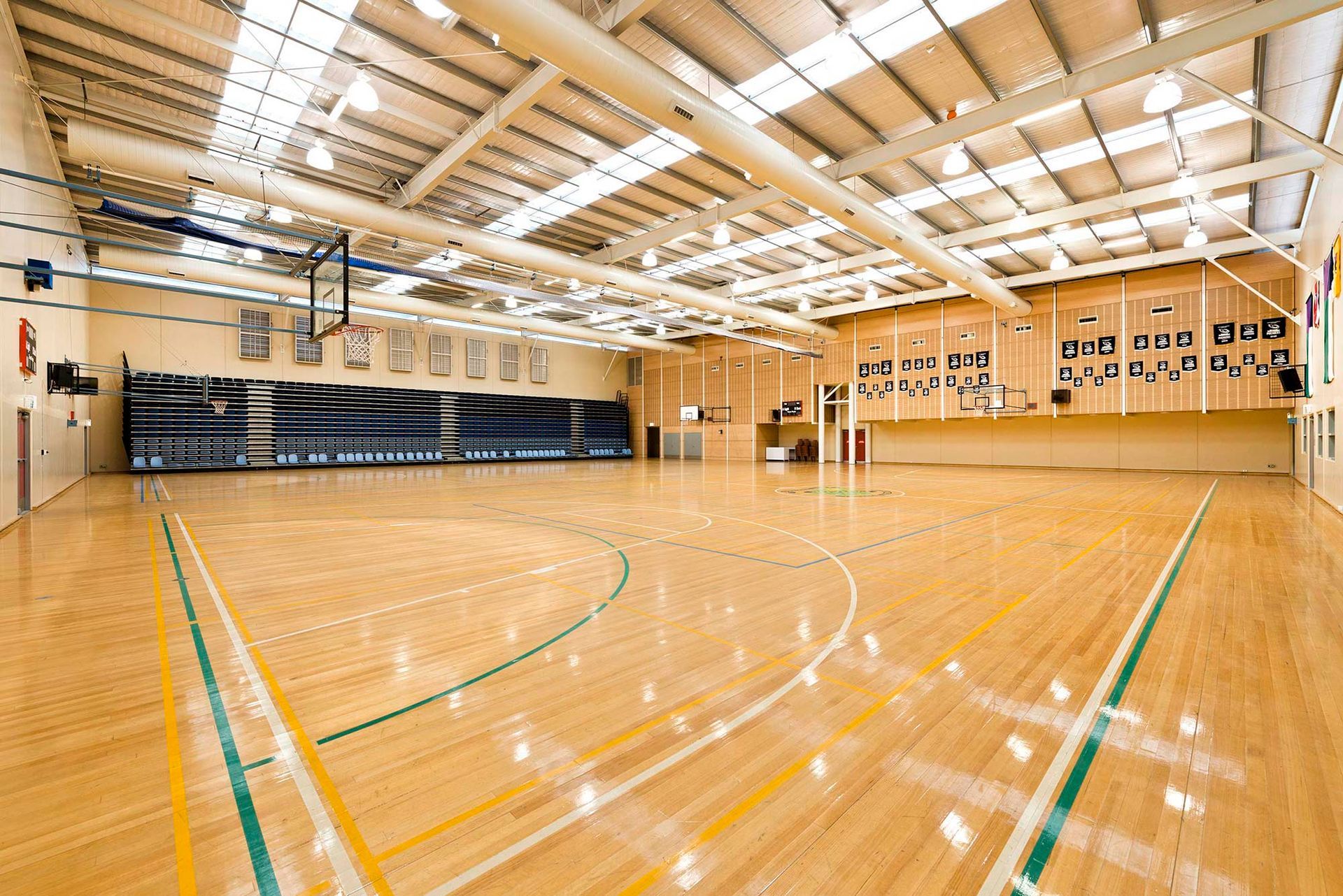 A large indoor basketball court with a wooden floor and a basketball hoop.