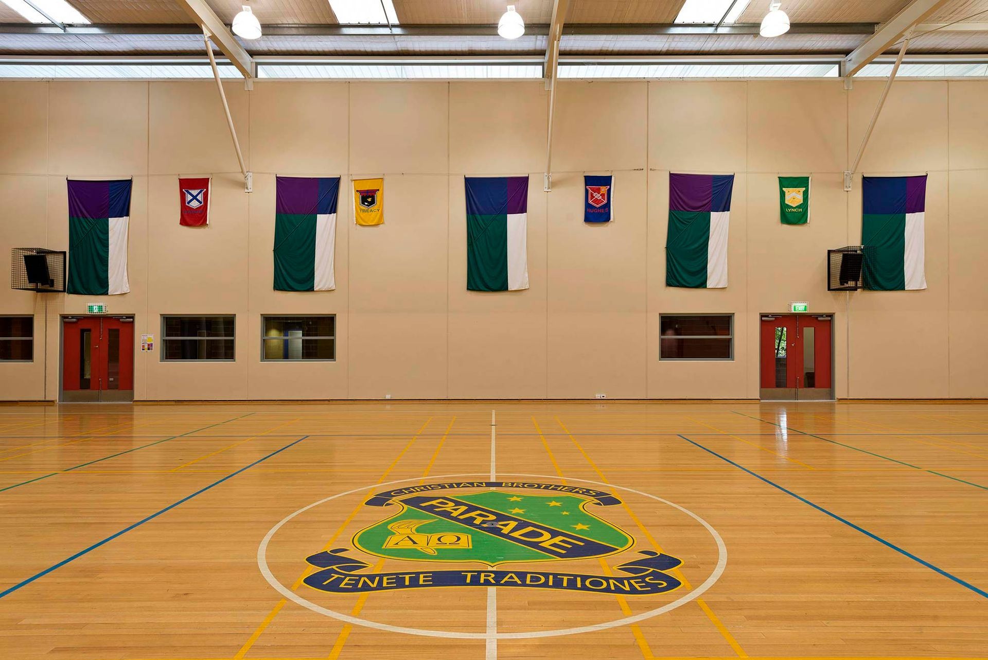 An empty gym with a basketball court and flags on the wall