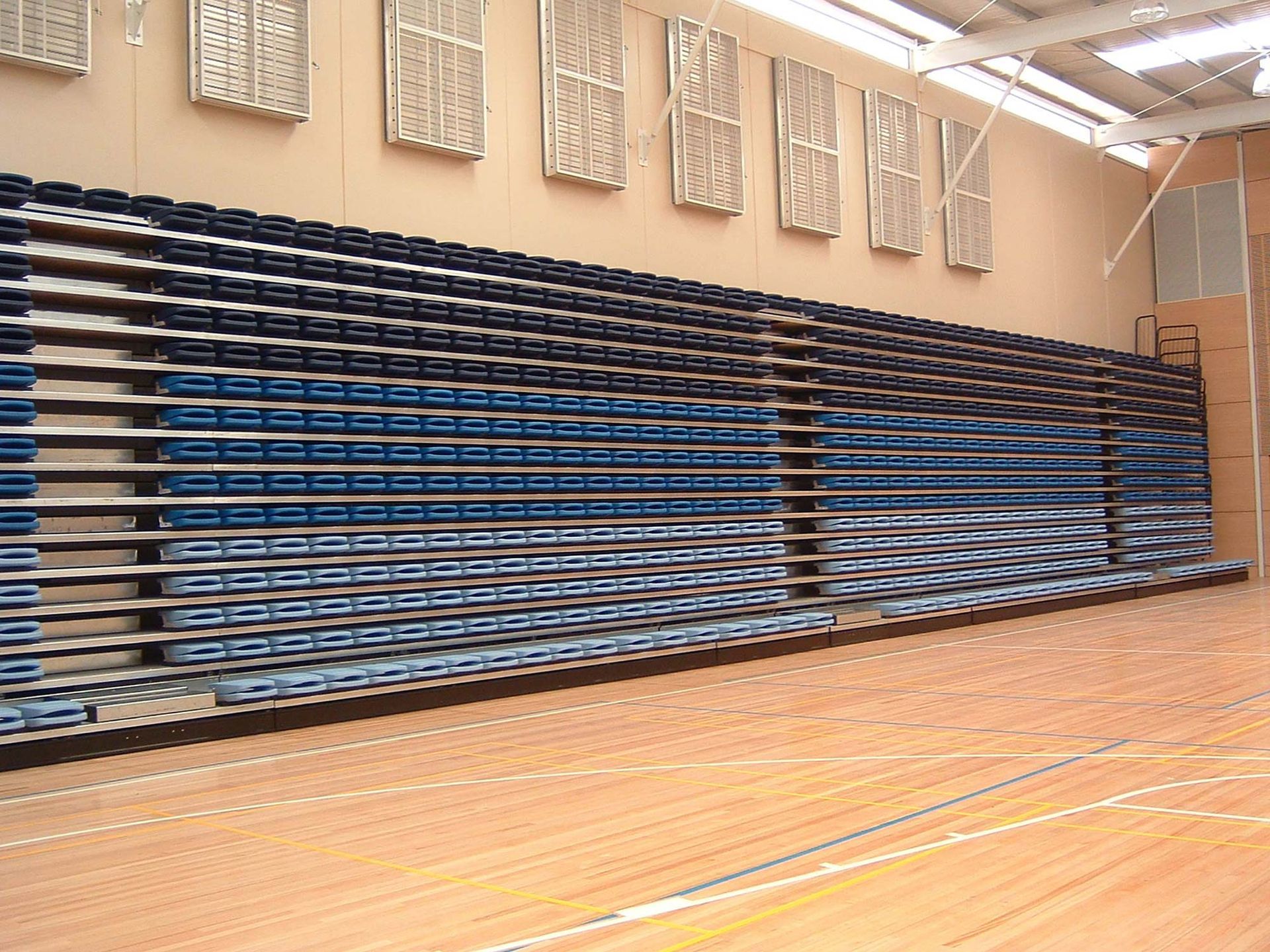 A basketball court with a wall of blue bleachers