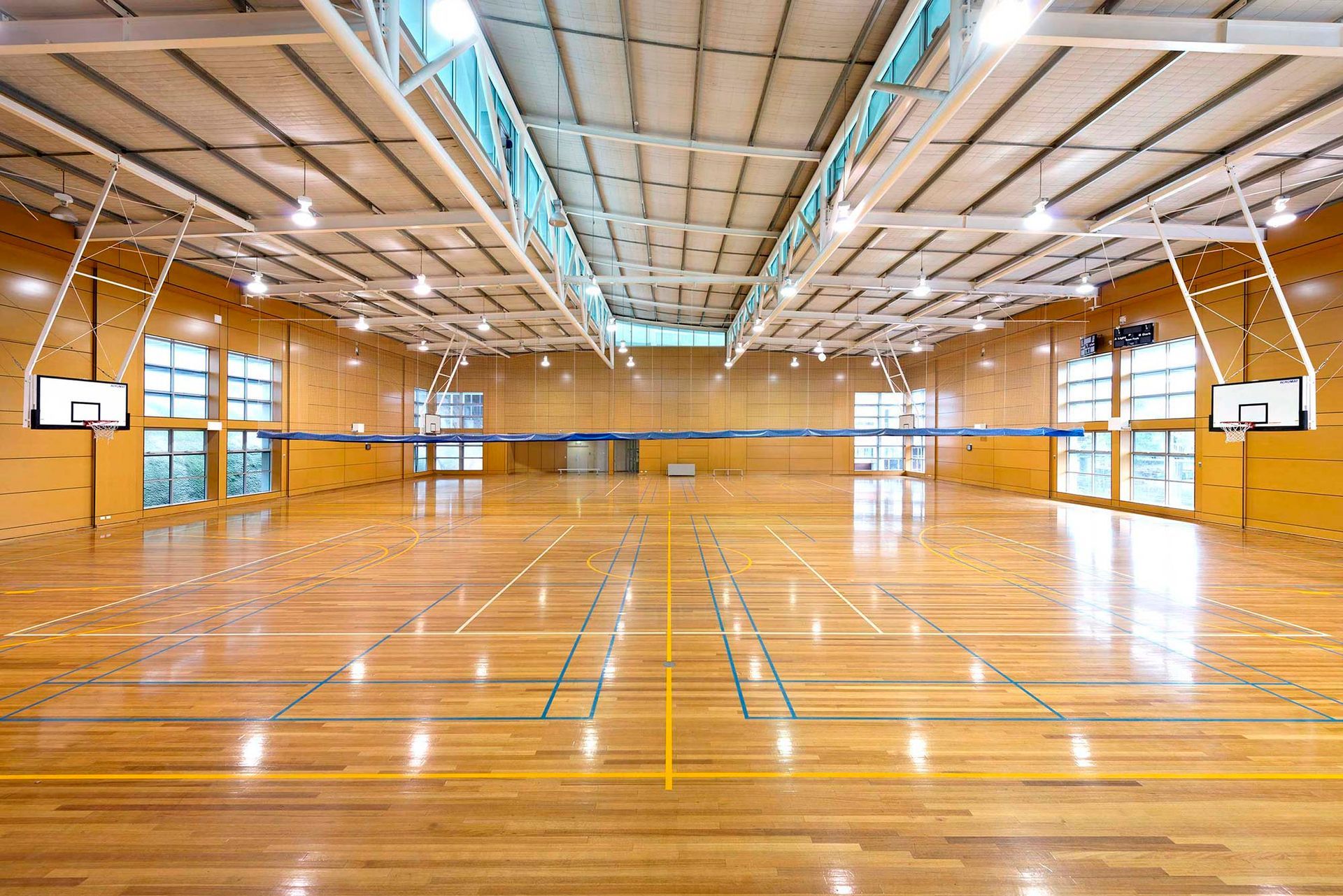 An empty basketball court with a wooden floor and a basketball hoop.