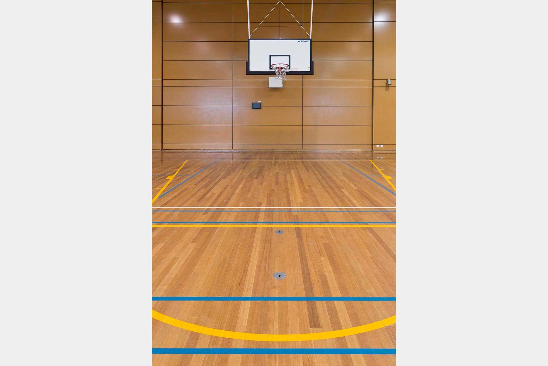 A basketball court with a wooden floor and a basketball hoop.