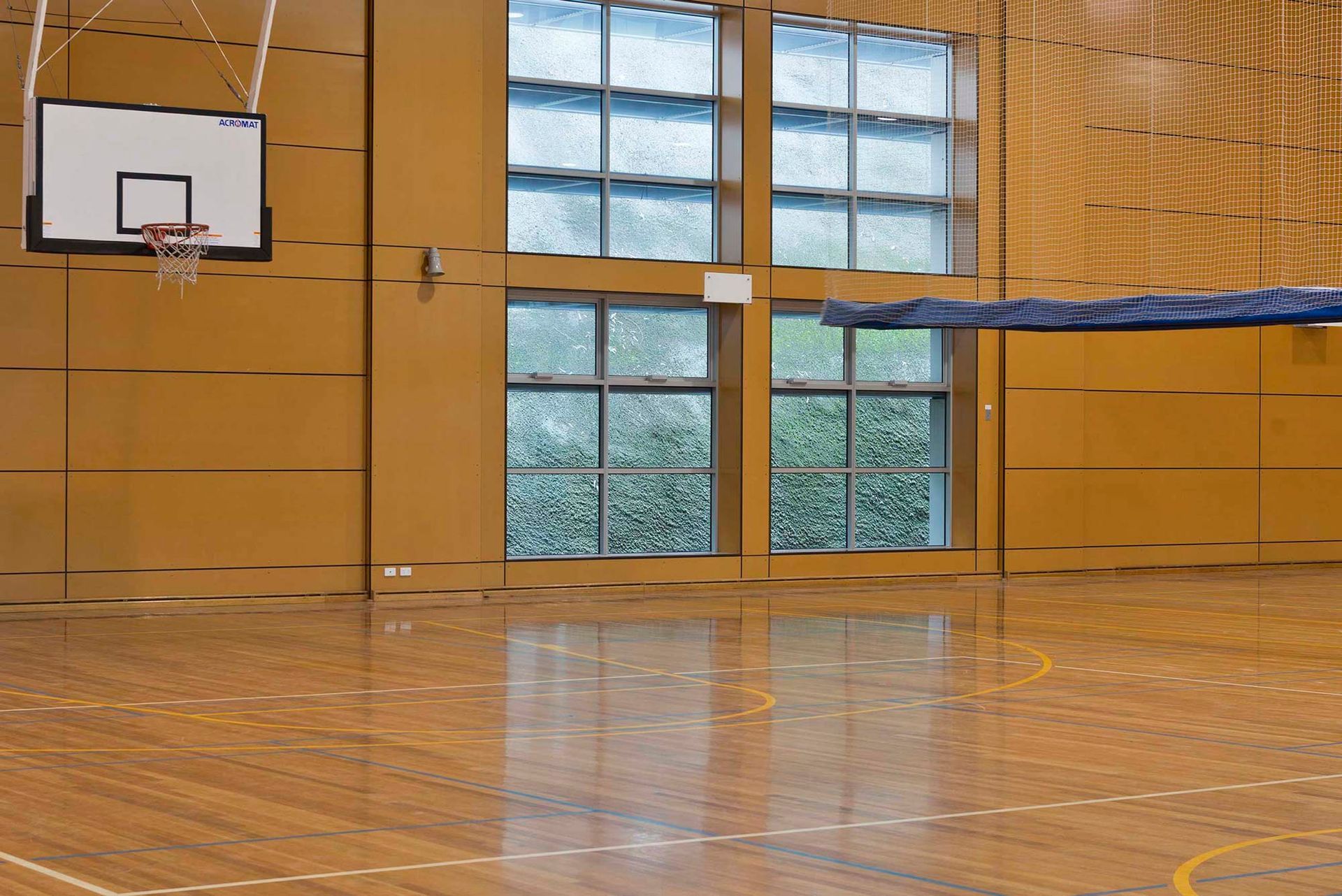 An empty basketball court with a basketball hoop hanging from the ceiling.