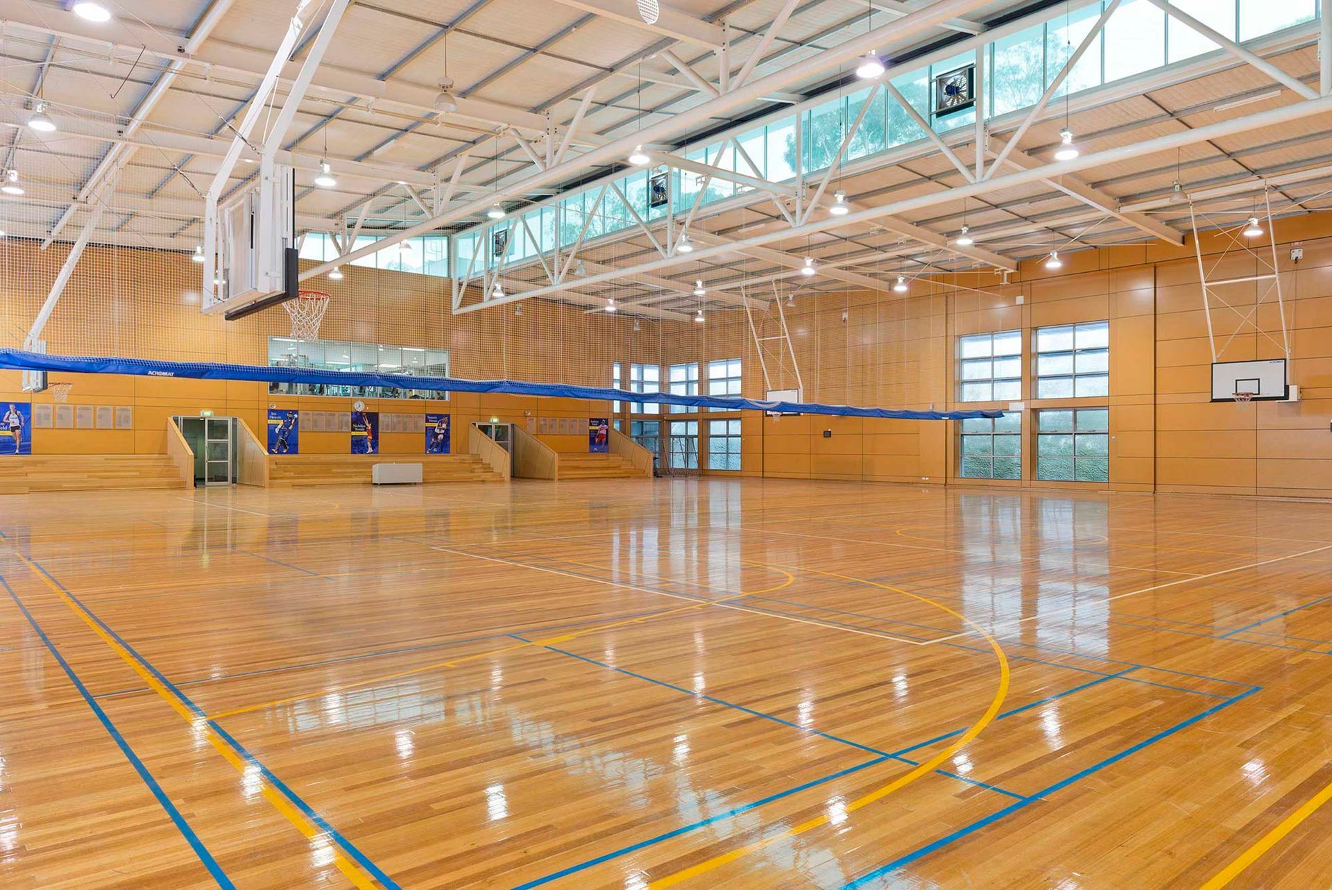 A large indoor basketball court with a wooden floor and a basketball hoop.