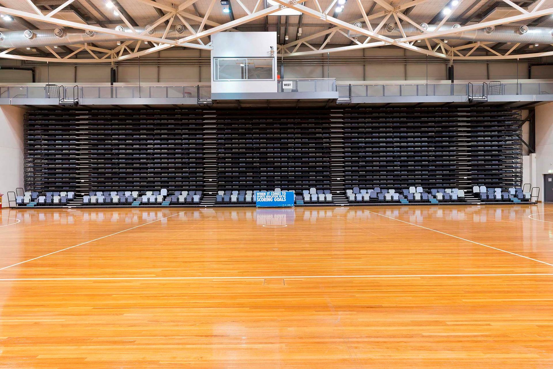 An empty basketball court with a wooden floor and bleachers.