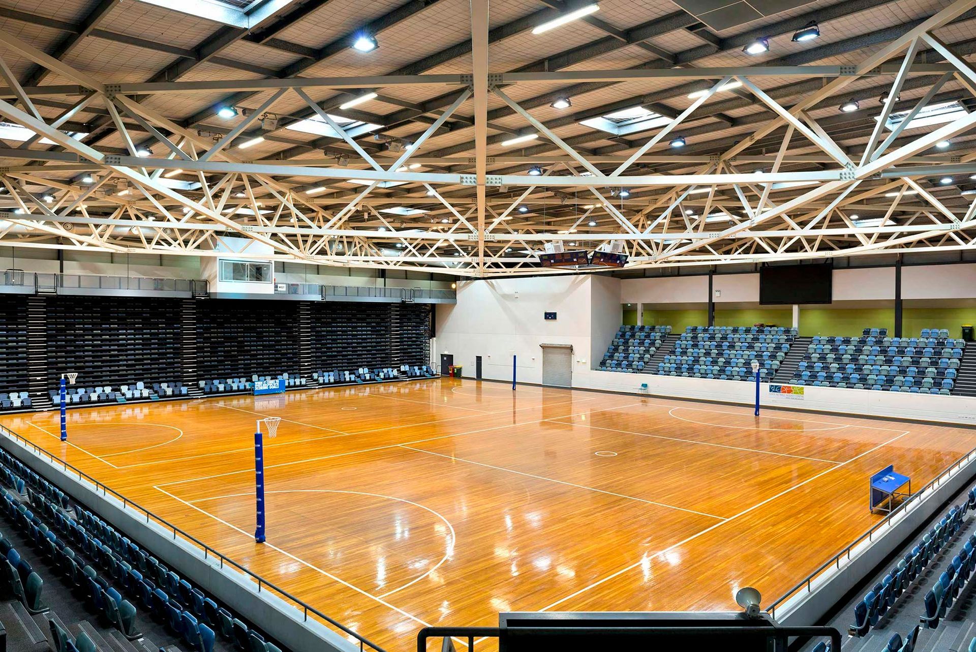 A large indoor gym with a wooden floor and bleachers.
