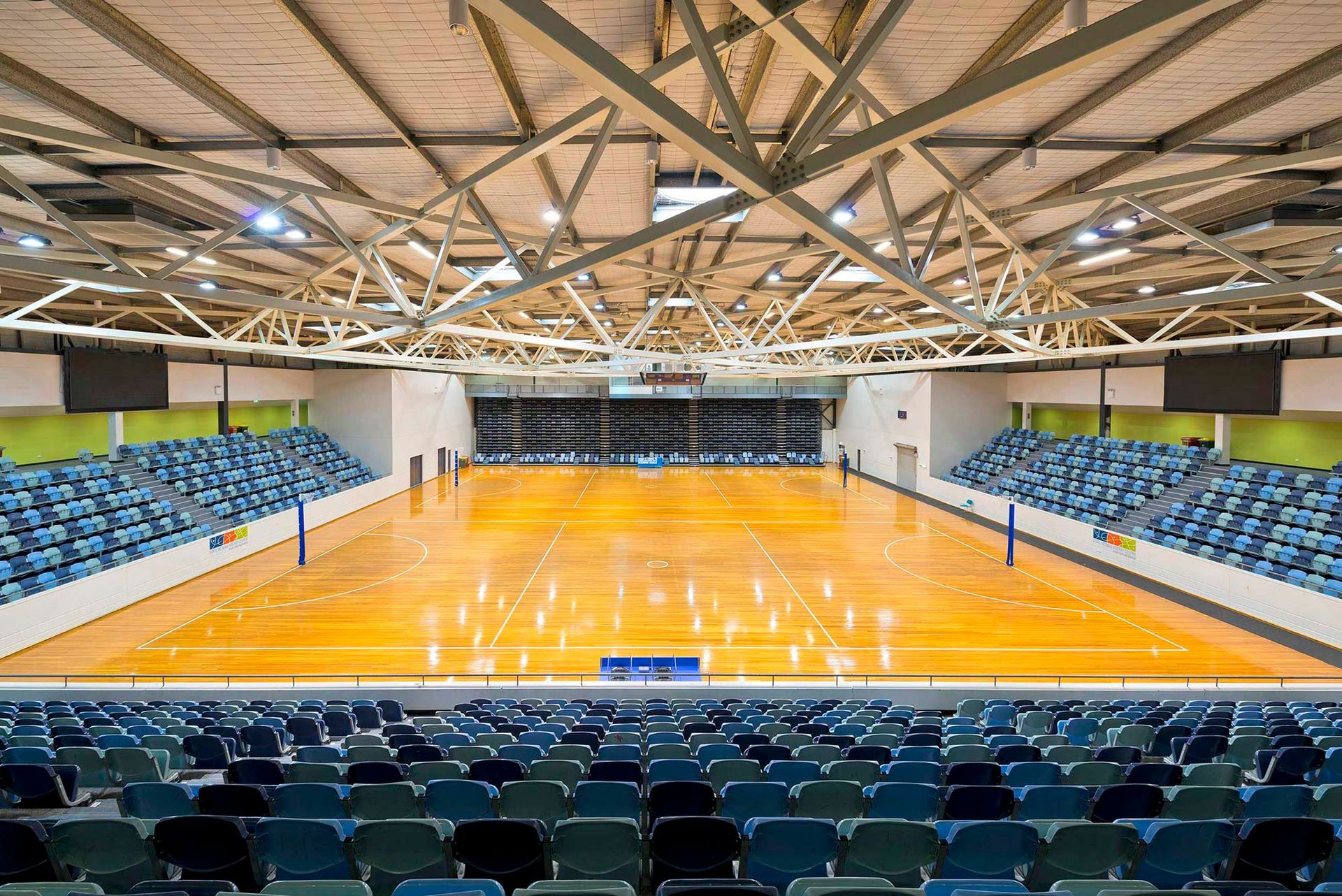 A large indoor basketball court with bleachers and a wooden floor.