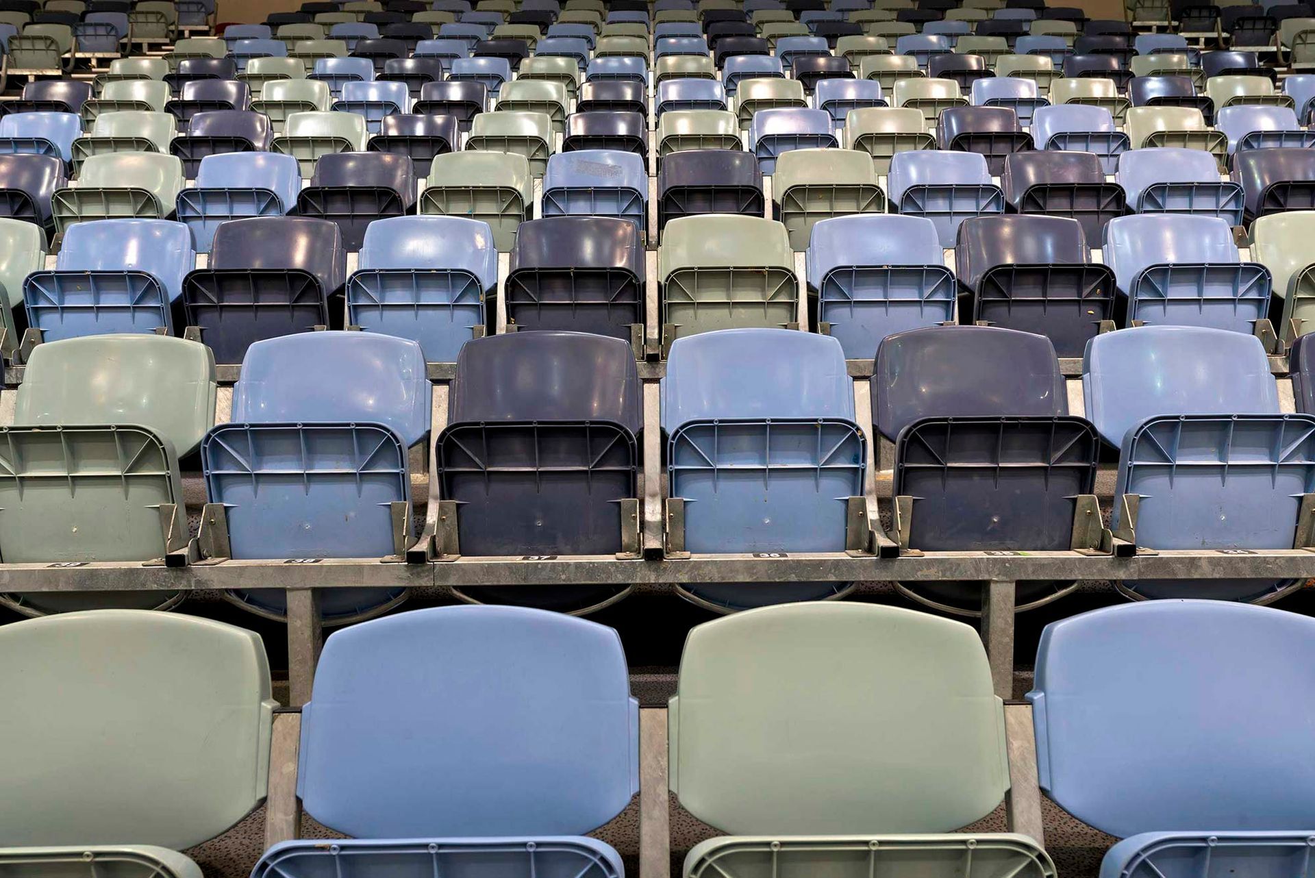 Rows of blue and green seats in a stadium