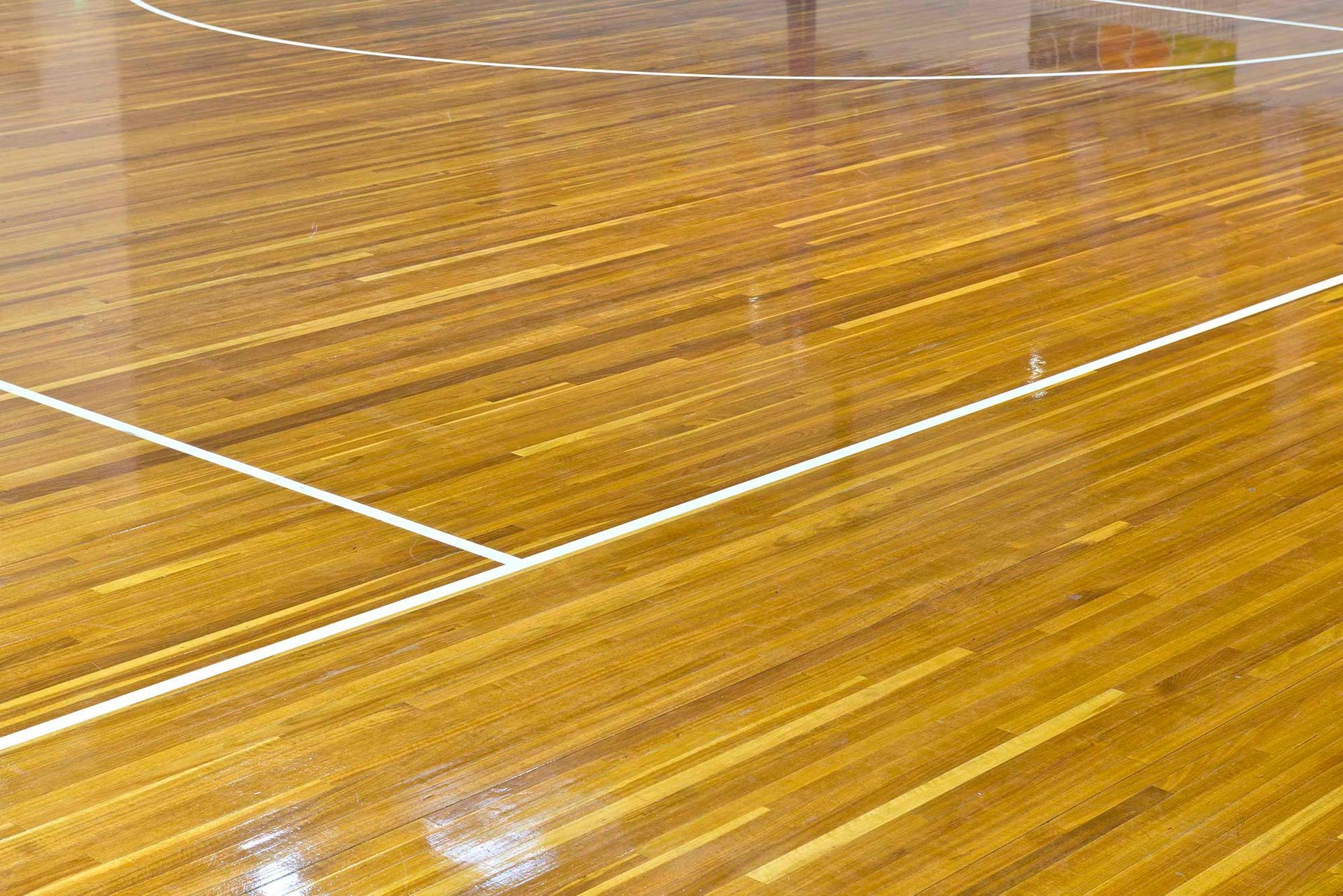 A basketball court with a wooden floor and white lines.