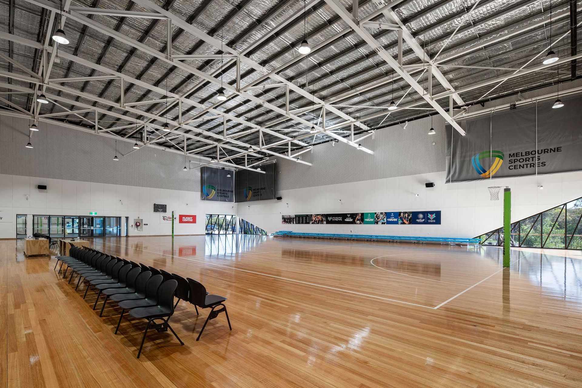 A large empty gym with a wooden floor and chairs.
