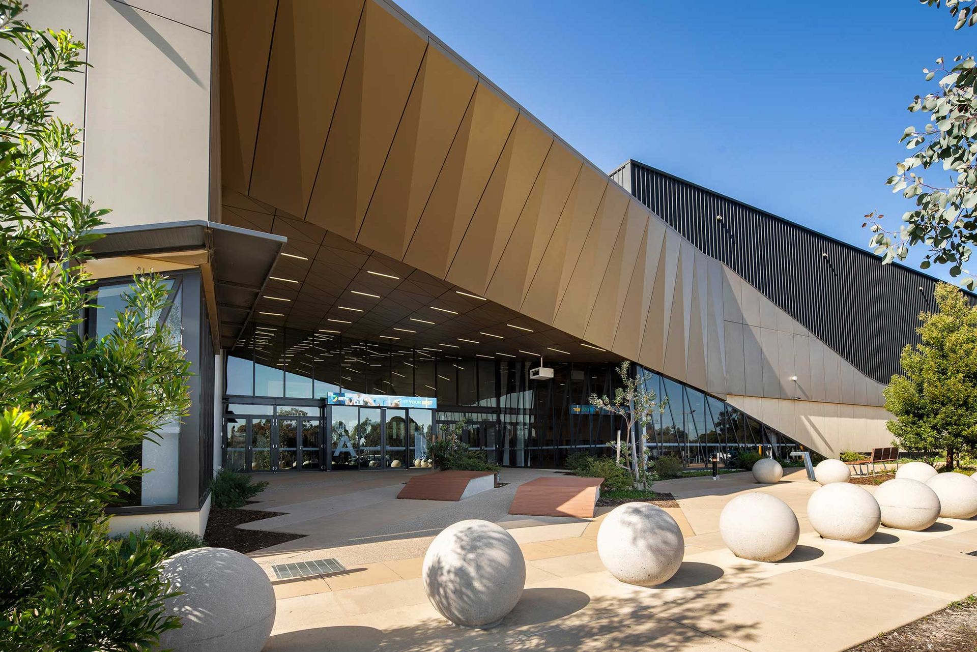 A large building with a lot of windows is surrounded by trees and balls.