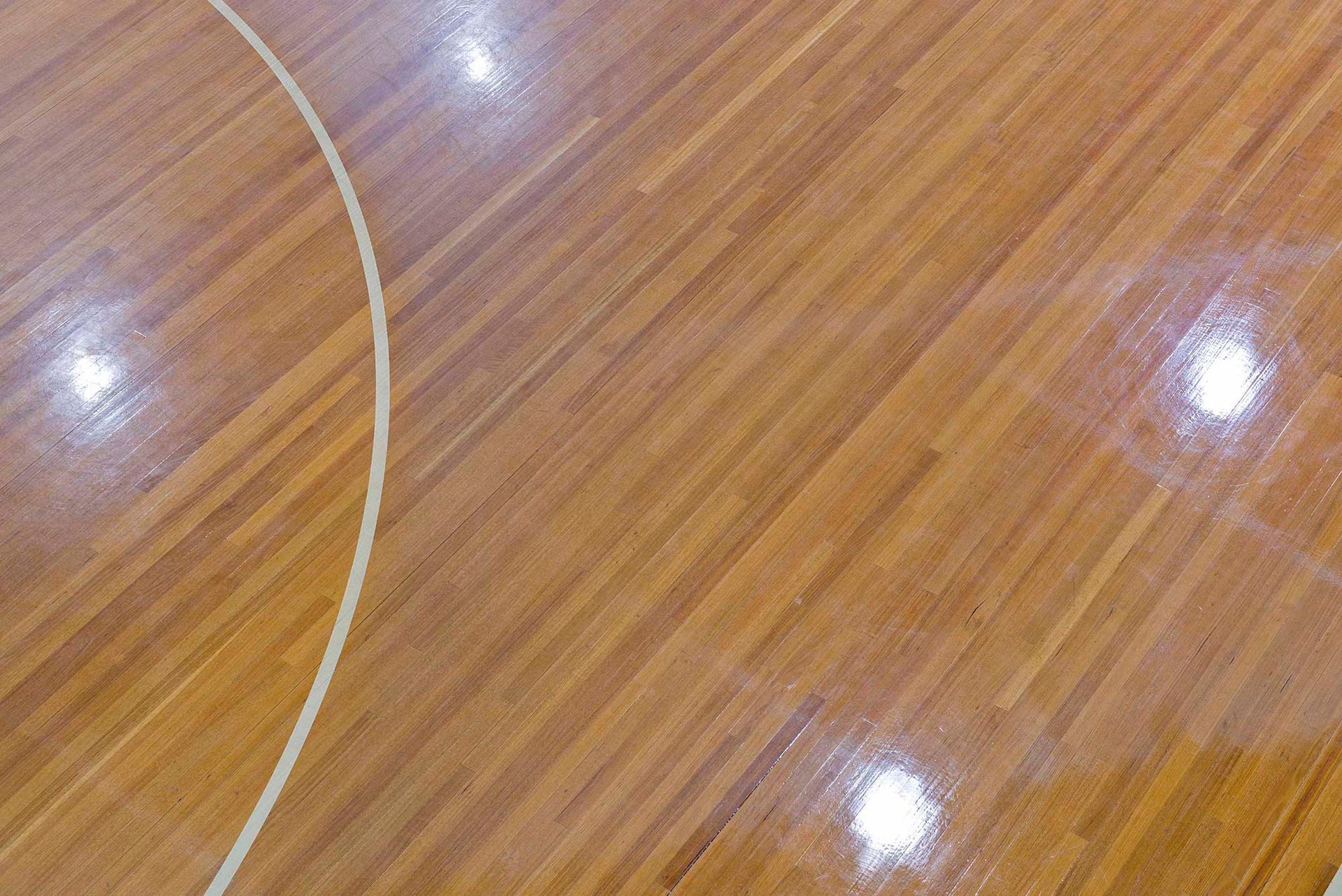 A basketball court with a wooden floor and a white line.