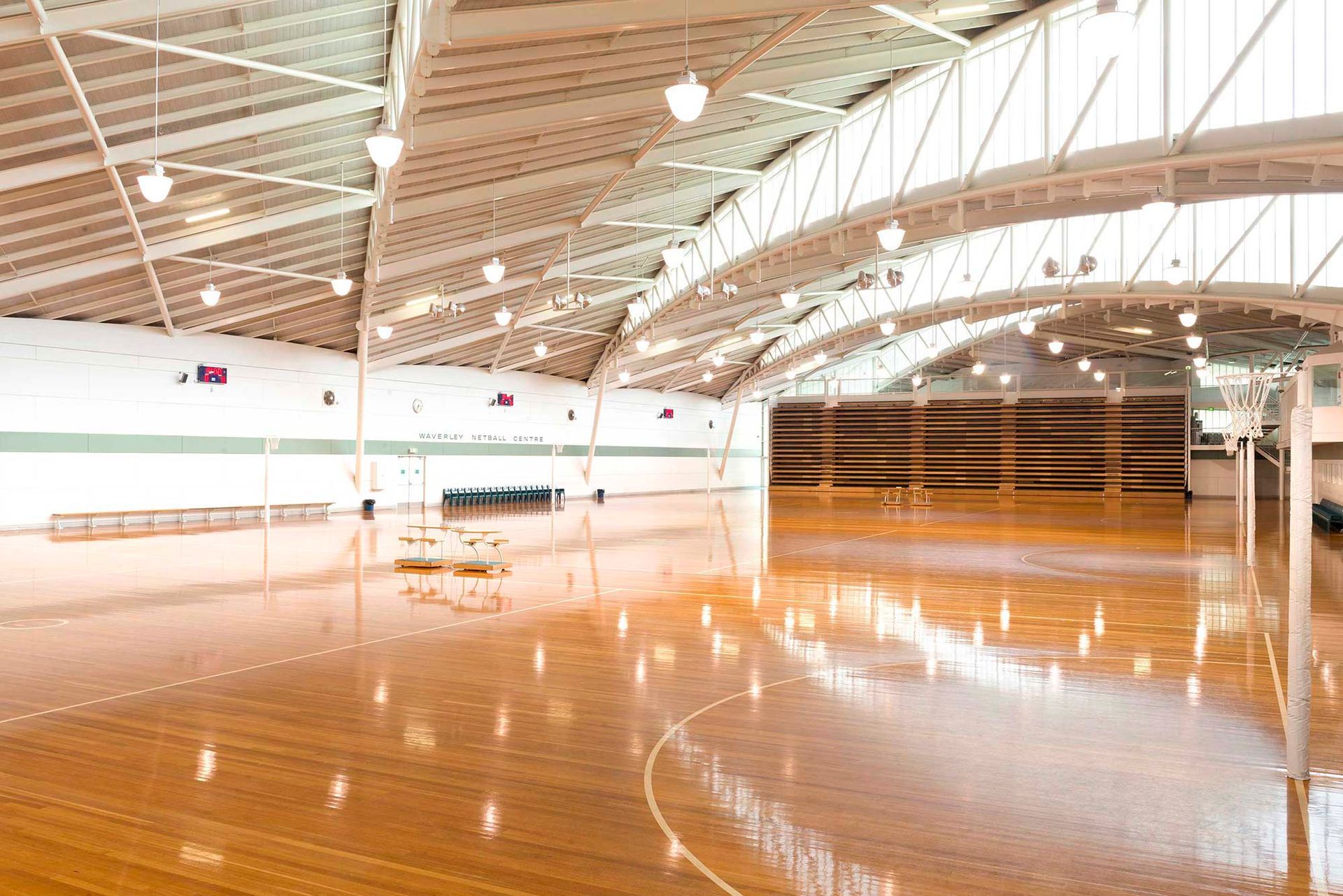 A large indoor basketball court with a wooden floor and a basketball hoop.