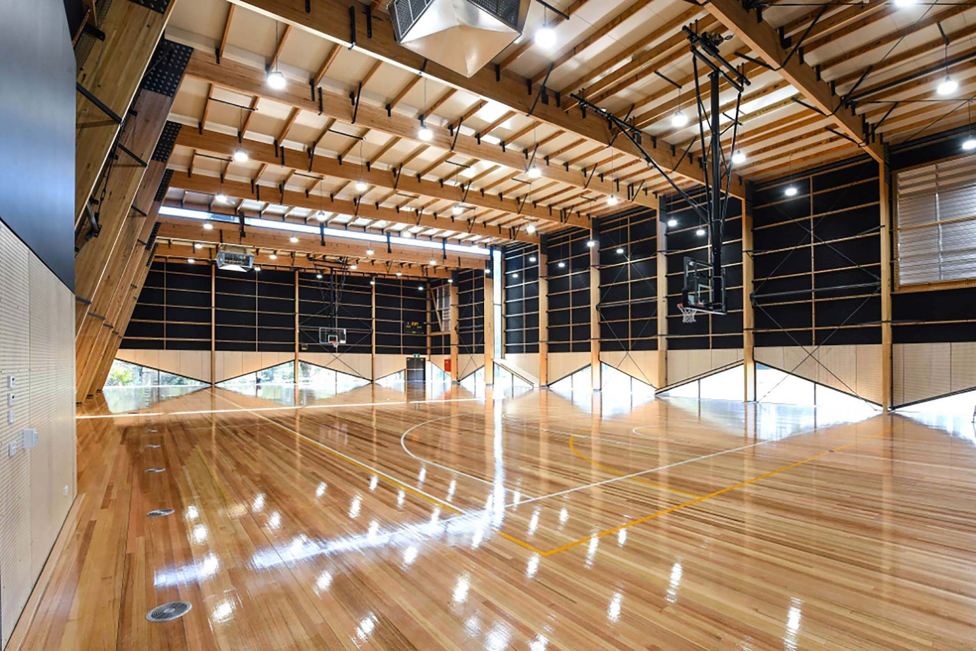 A large indoor basketball court with a wooden floor and a basketball hoop.