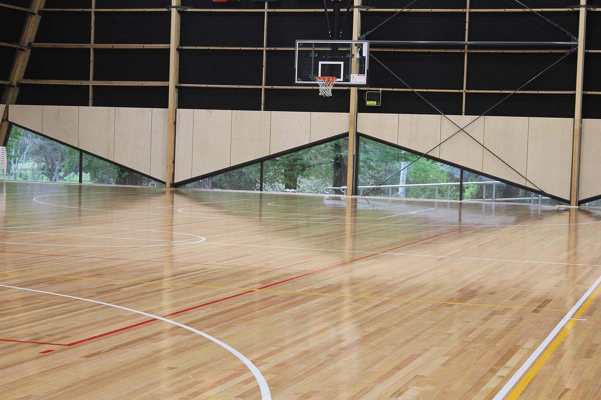 A basketball court with a wooden floor and a basketball hoop