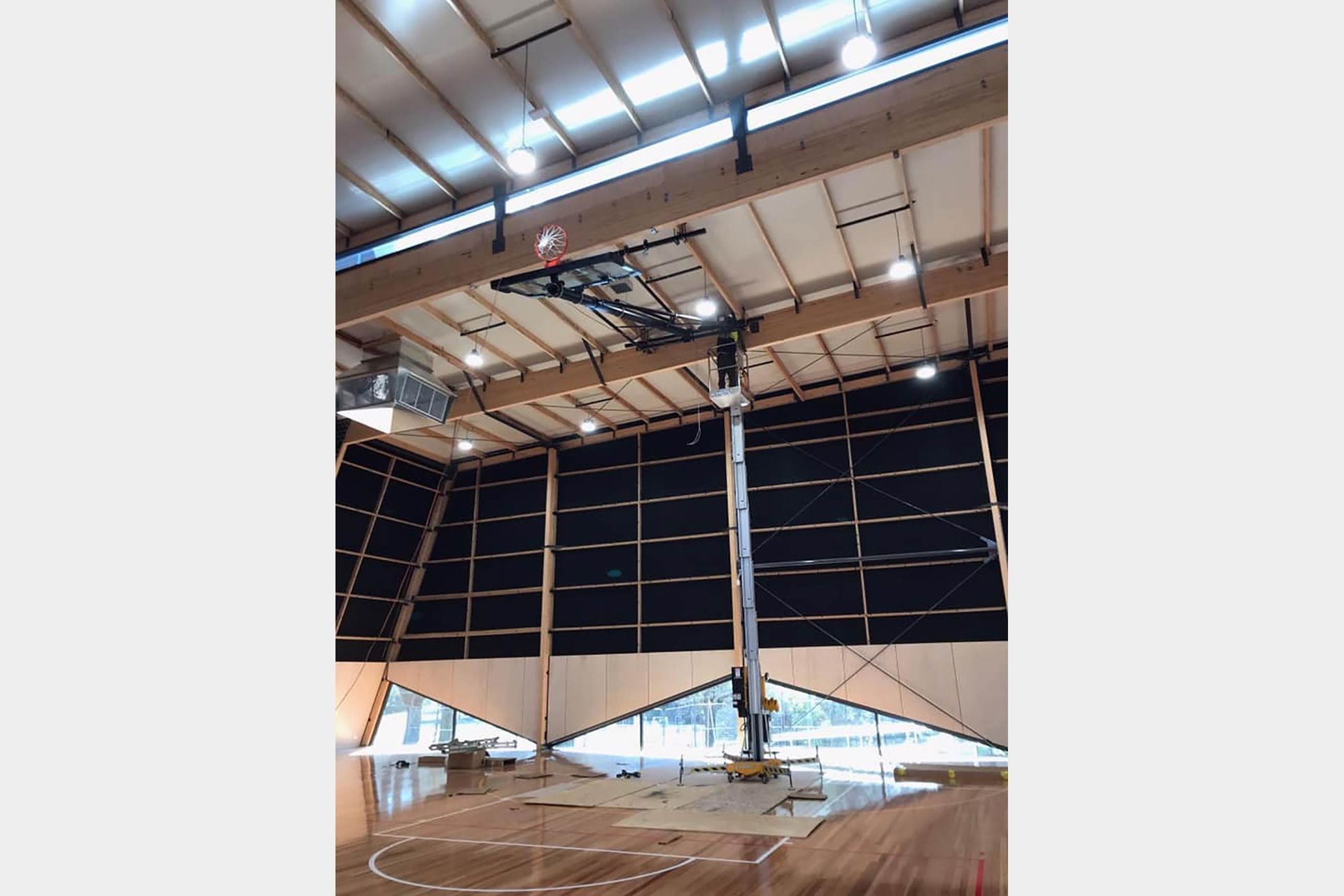 A basketball hoop is hanging from the ceiling of a gym.