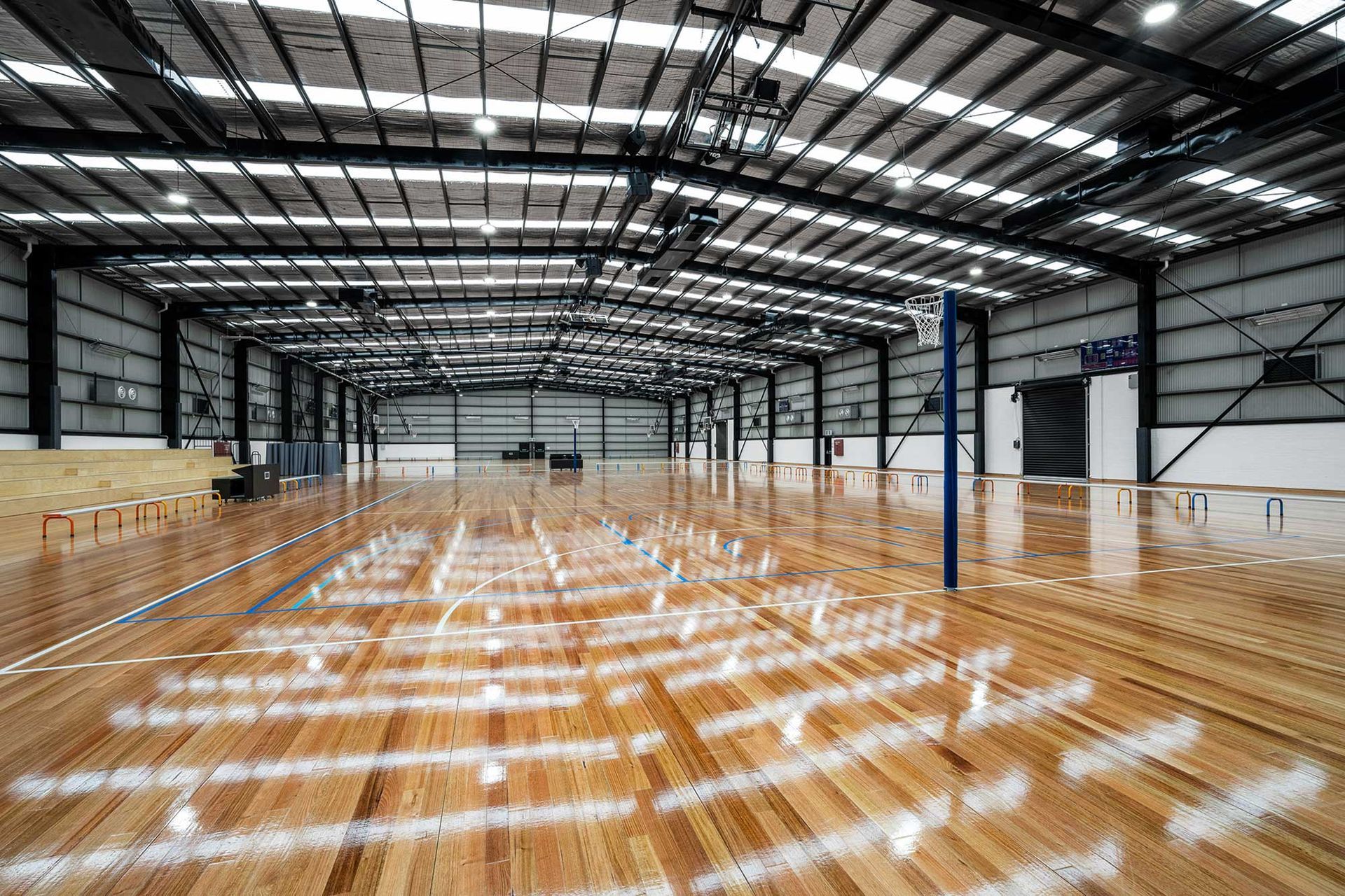 A large empty warehouse with a wooden floor and a volleyball net.